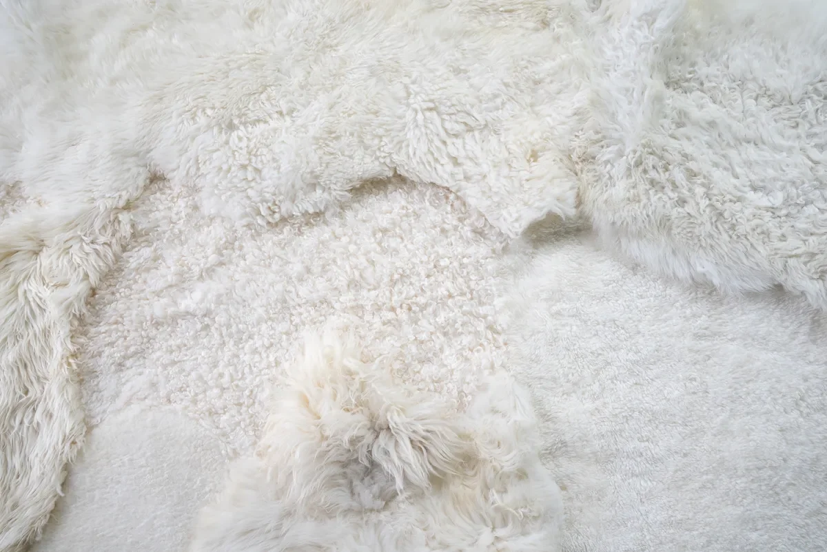 Sjoe by Wol Society, a near-square white sheepskin rug with smooth, curly and fluffy patches