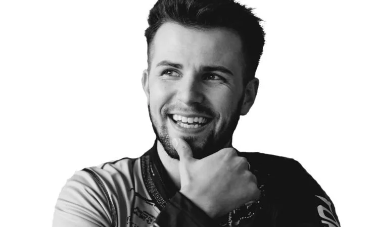 A man smiling with his hand on his chin in a black and white photo.