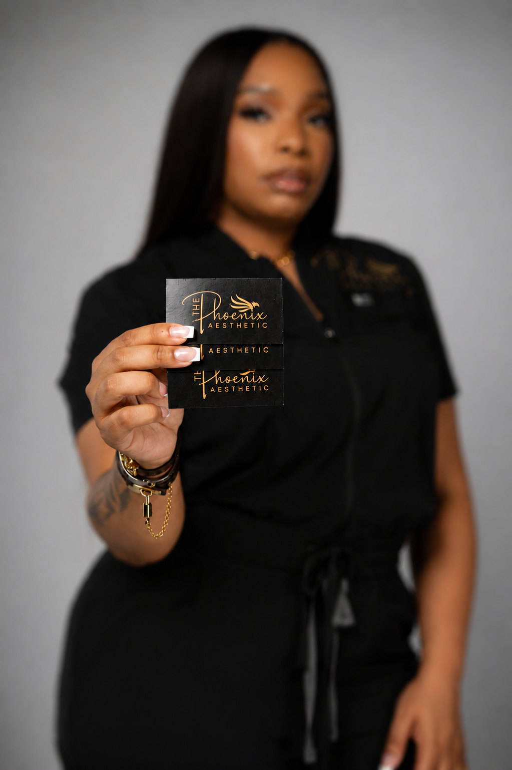 Licensed esthetician Amber, founder of The Phoenix Aesthetic, holding business cards for her luxury skincare studio offering customized facials, dermaplaning, brow services, and waxing in the College Park area of metro Atlanta near Hartsfield-Jackson