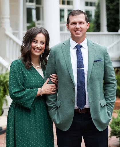 Victoria and Randy of The Kiker Group standing outside a white home with a front porch in Monroe, NC.