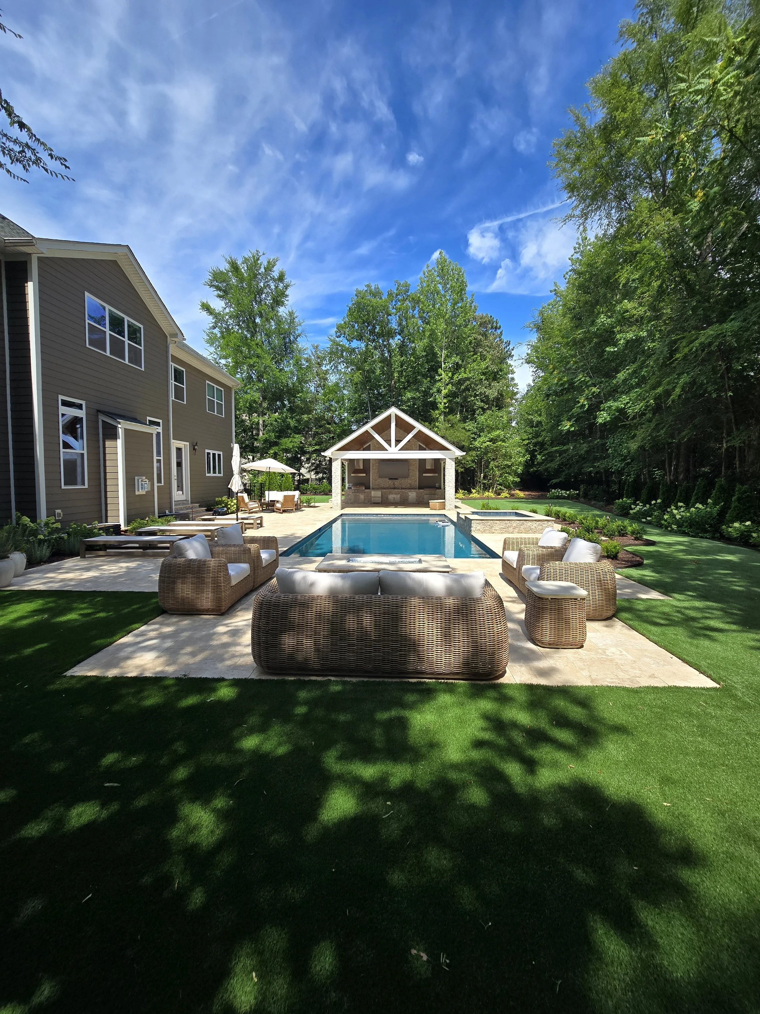 Custom outdoor living space by The Kiker Group near Monroe, NC, featuring a swimming pool, patio seating, and gazebo with an outdoor kitchen.