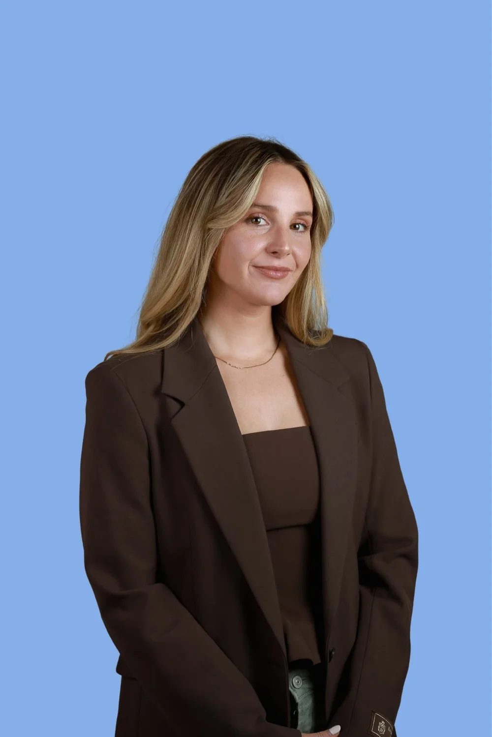 Emily Dubbe, marketing coach for therapists, in a brown blazer against a blue background