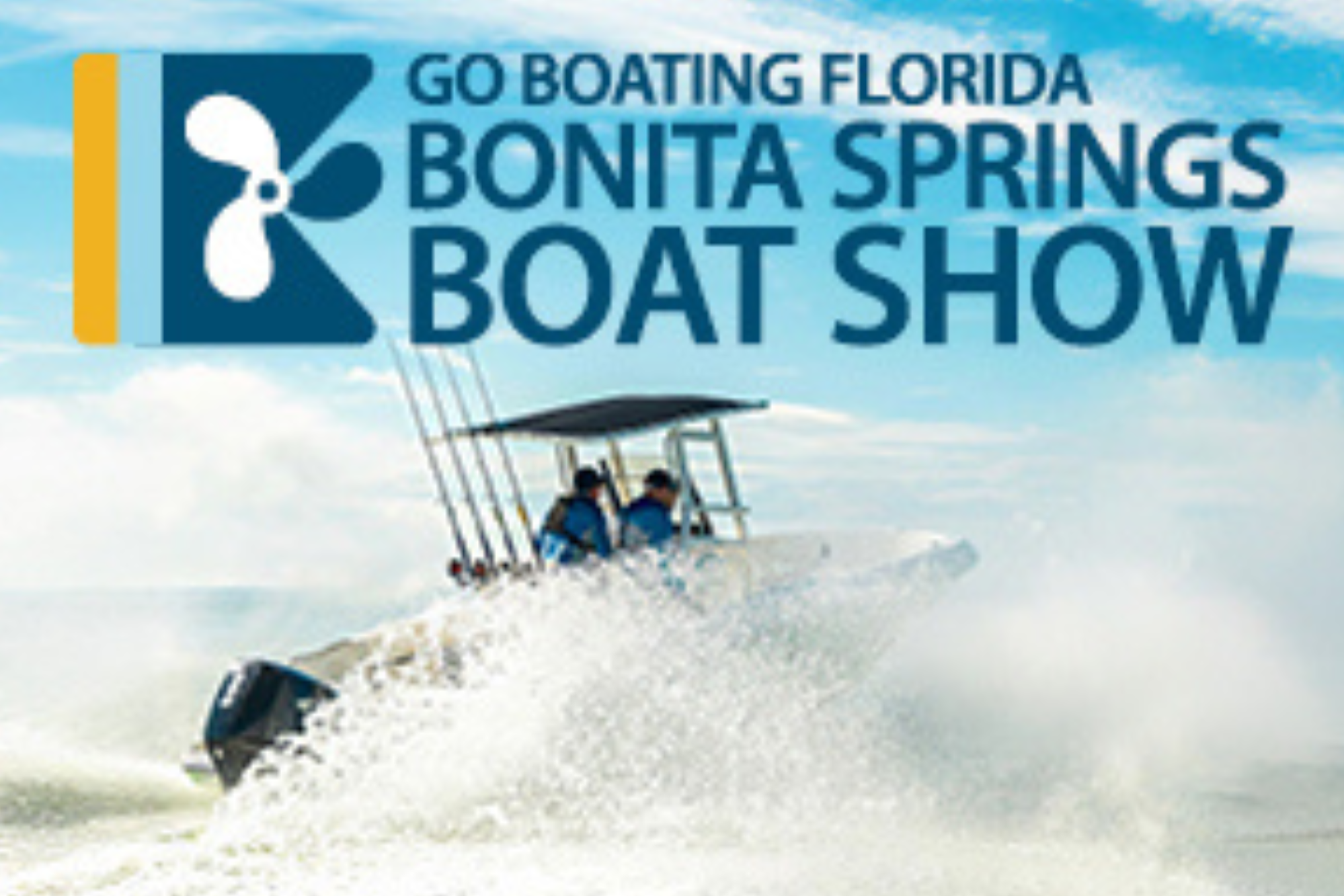 Two people riding a snowmobile across snow in front of a sign that reads 'Go Boating Florida Bonita Springs Boat Show' with a blue sky background.