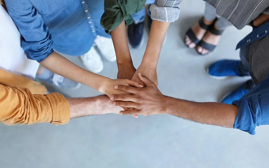 Group of diverse people stacking their hands together in a gesture of teamwork and unity.