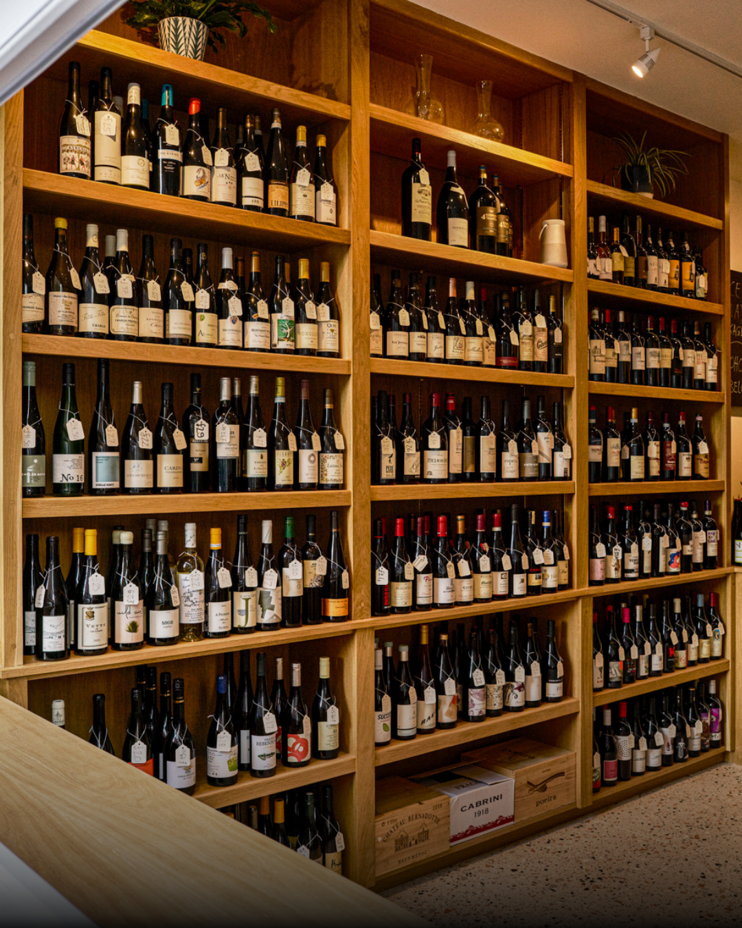 Wooden wine shelves filled with bottles of wine in a wine shop.