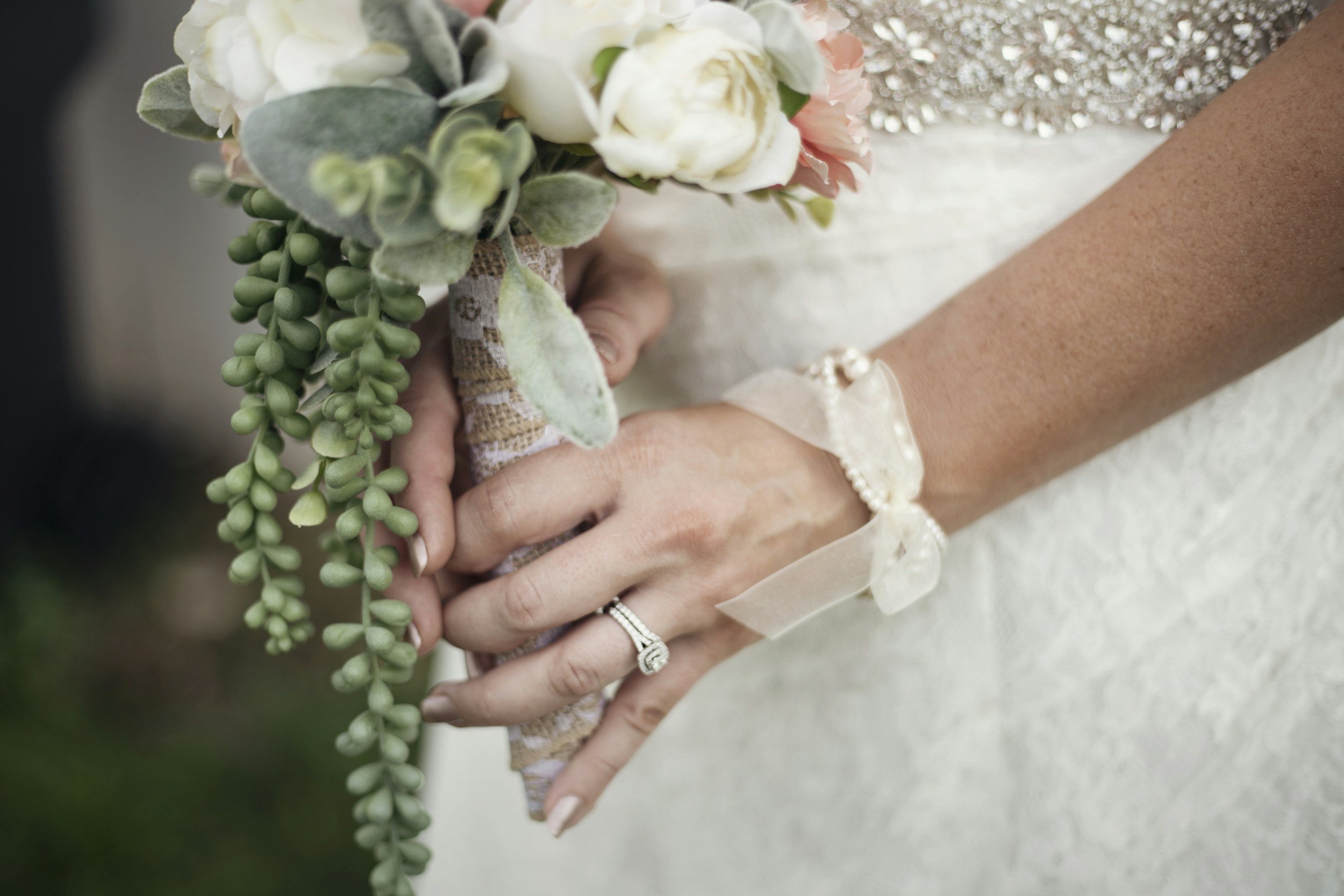 Bride holding a bouquet of white and pink flowers with greenery.