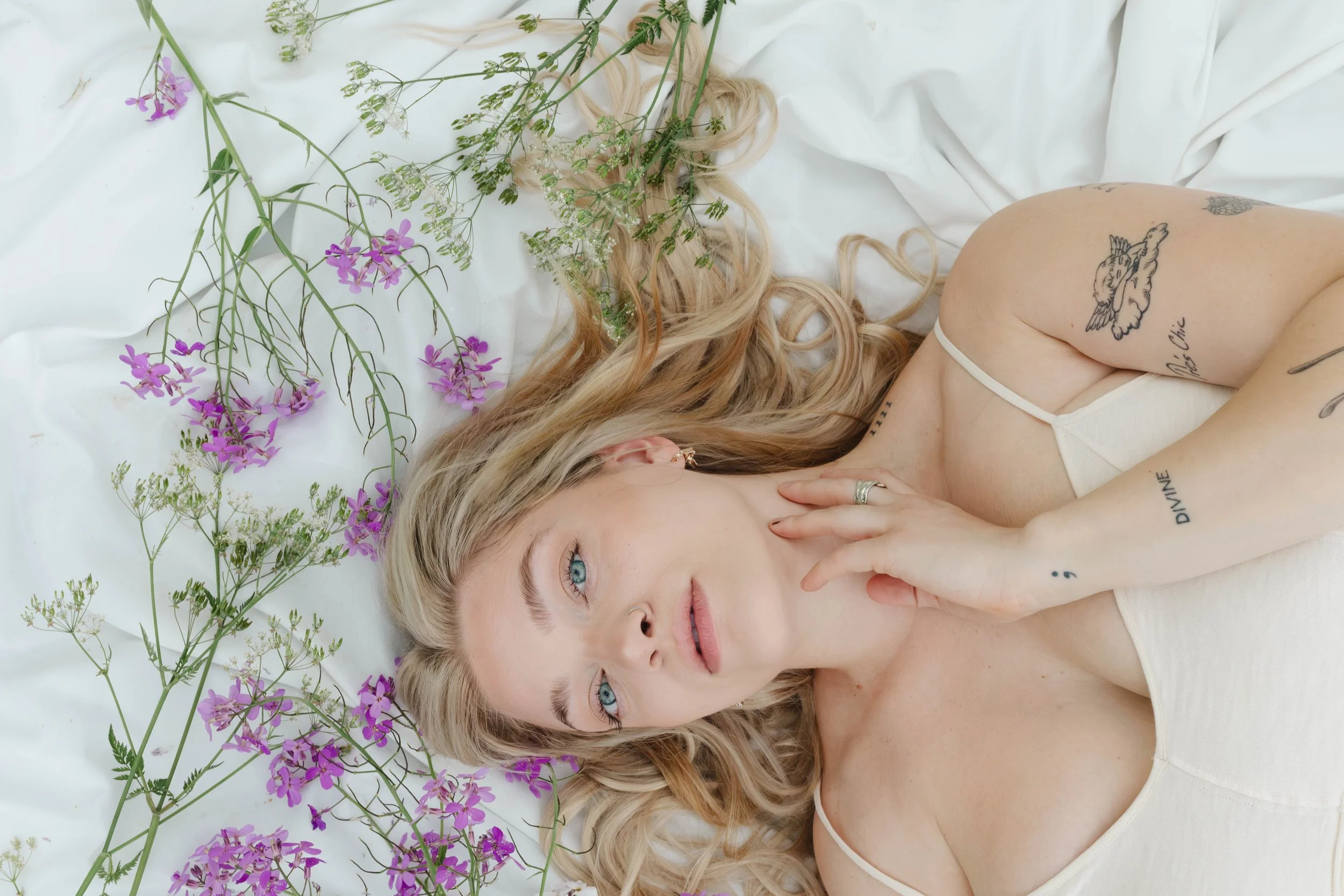 Blonde woman lying among purple flowers in a soft romantic portrait