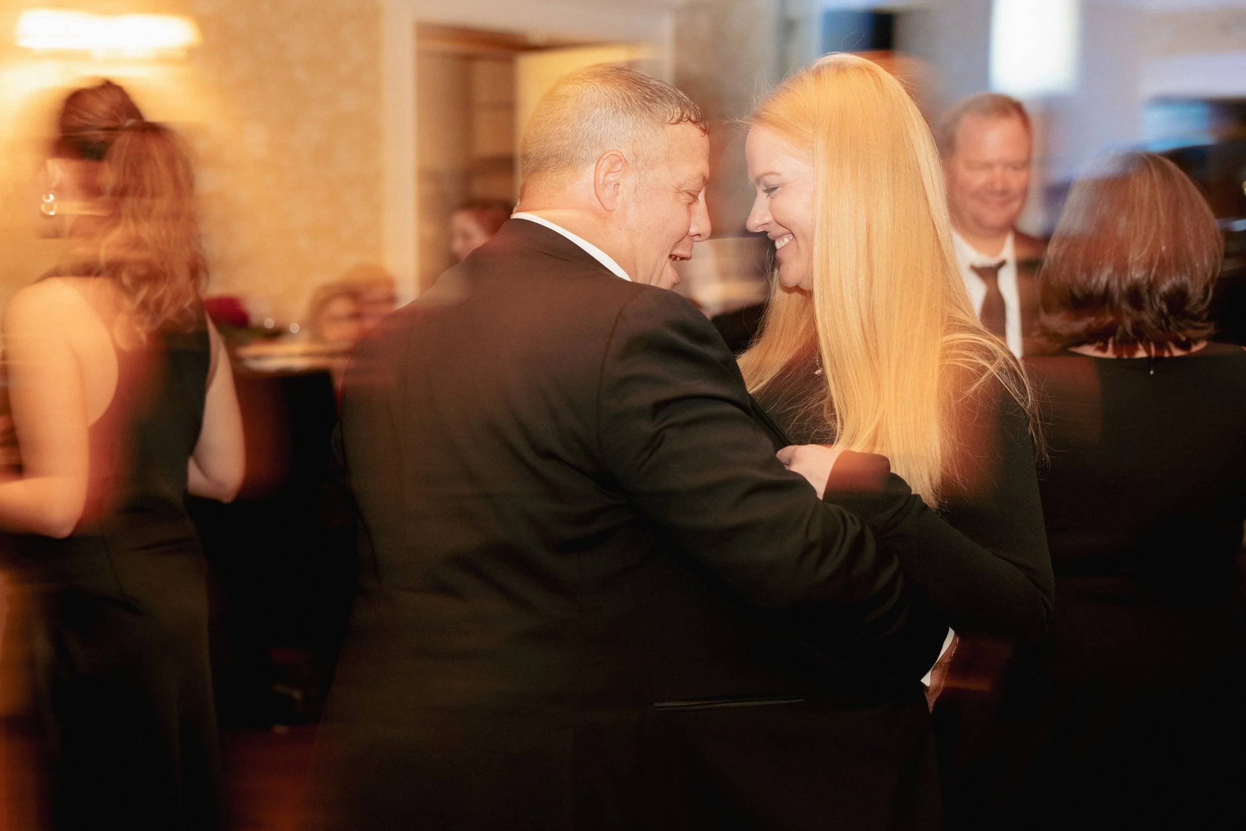 Candid photo of a couple laughing together at a formal celebration