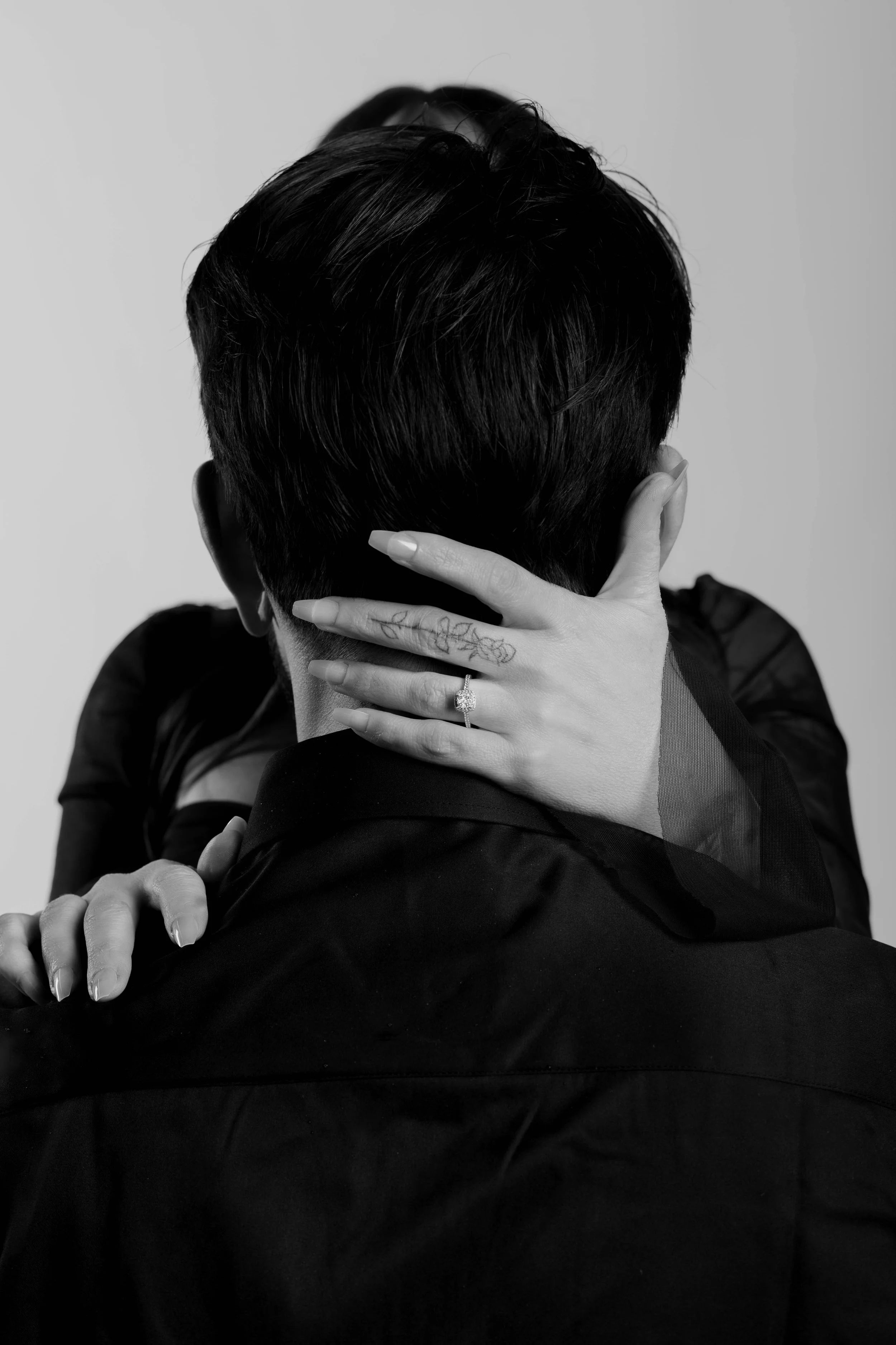 Black and white photo of a couple in an intimate embrace, her hand on the back of his head