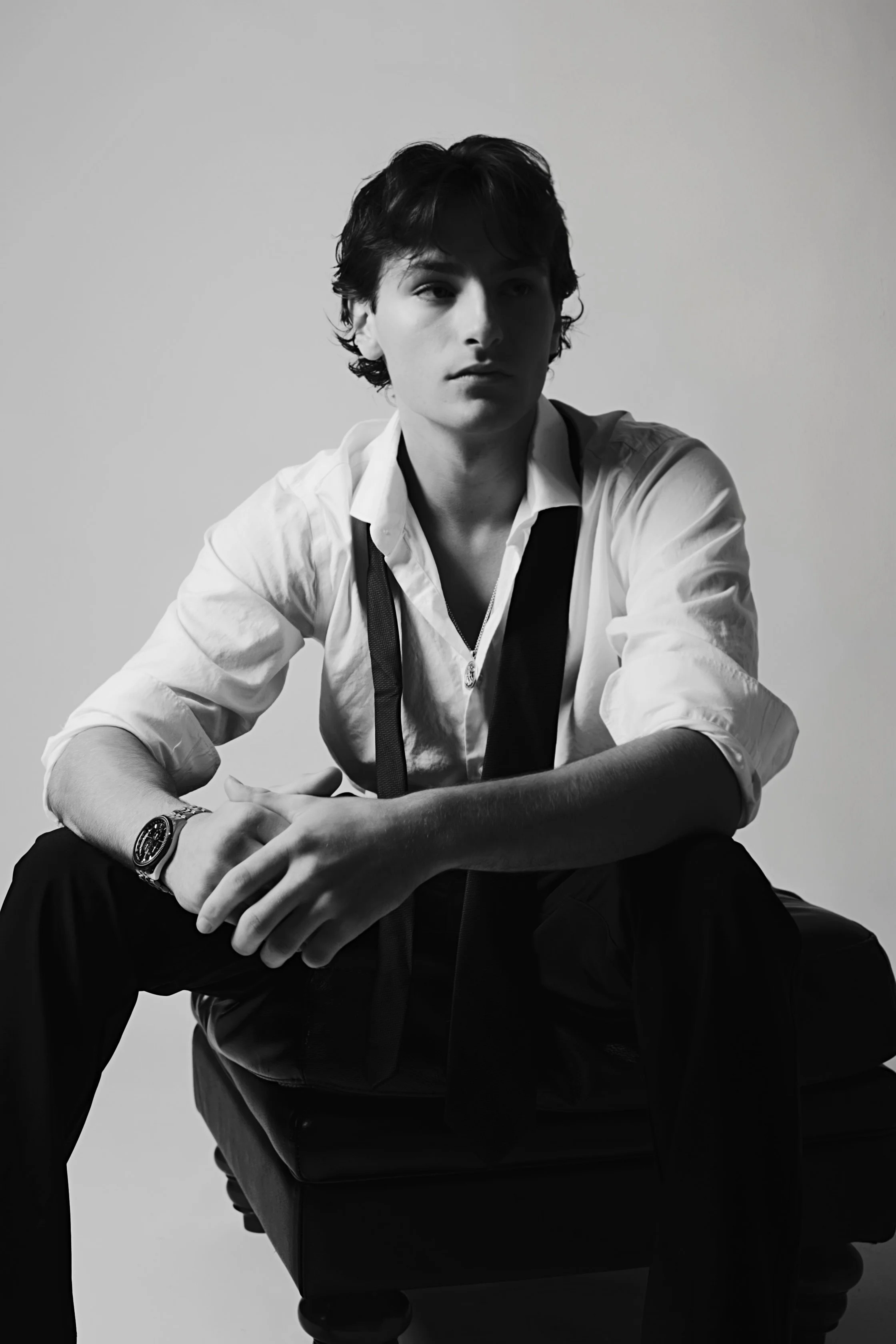 Black and white portrait of a young man seated and looking off camera by Lillie Ruth Photography
