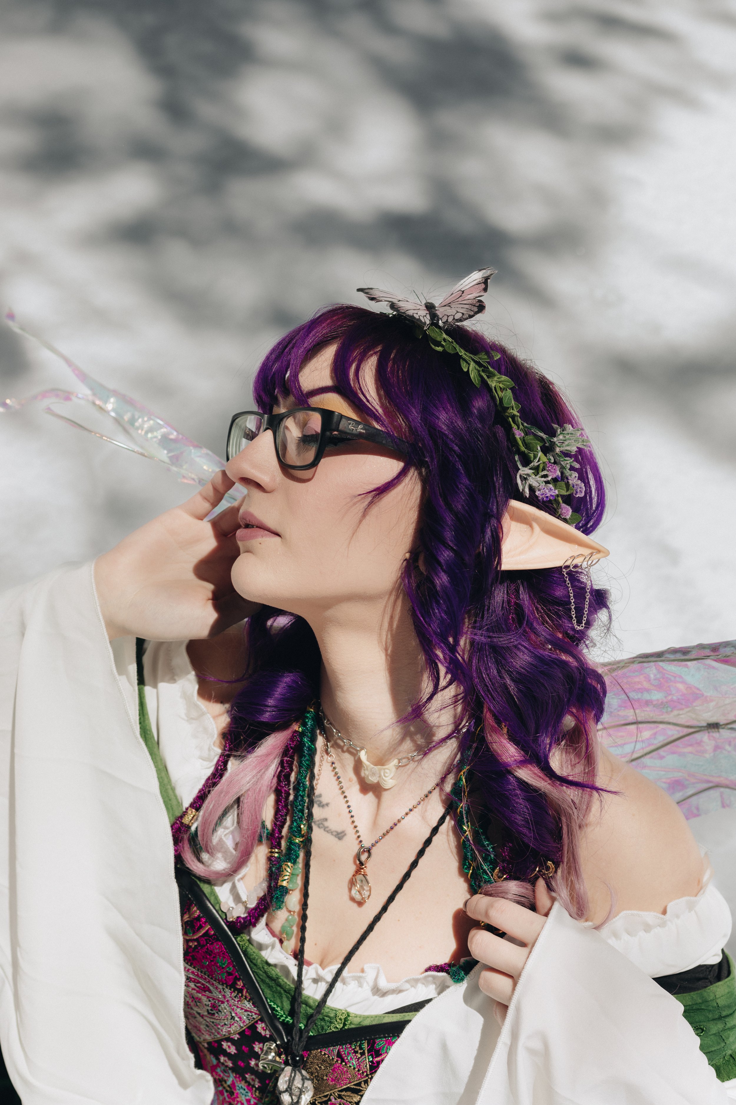 Woman with purple hair, fairy wings, and pointed ears in a whimsical fantasy portrait
