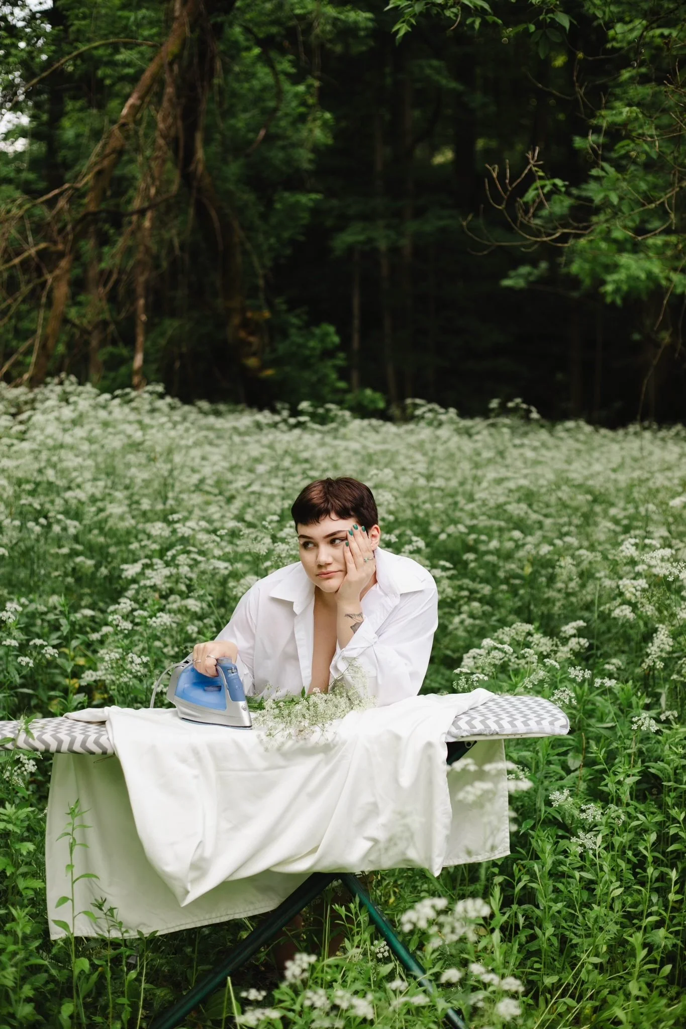 Lillie Ruth ironing on an ironing board in a field of flowers in a playful editorial portrait