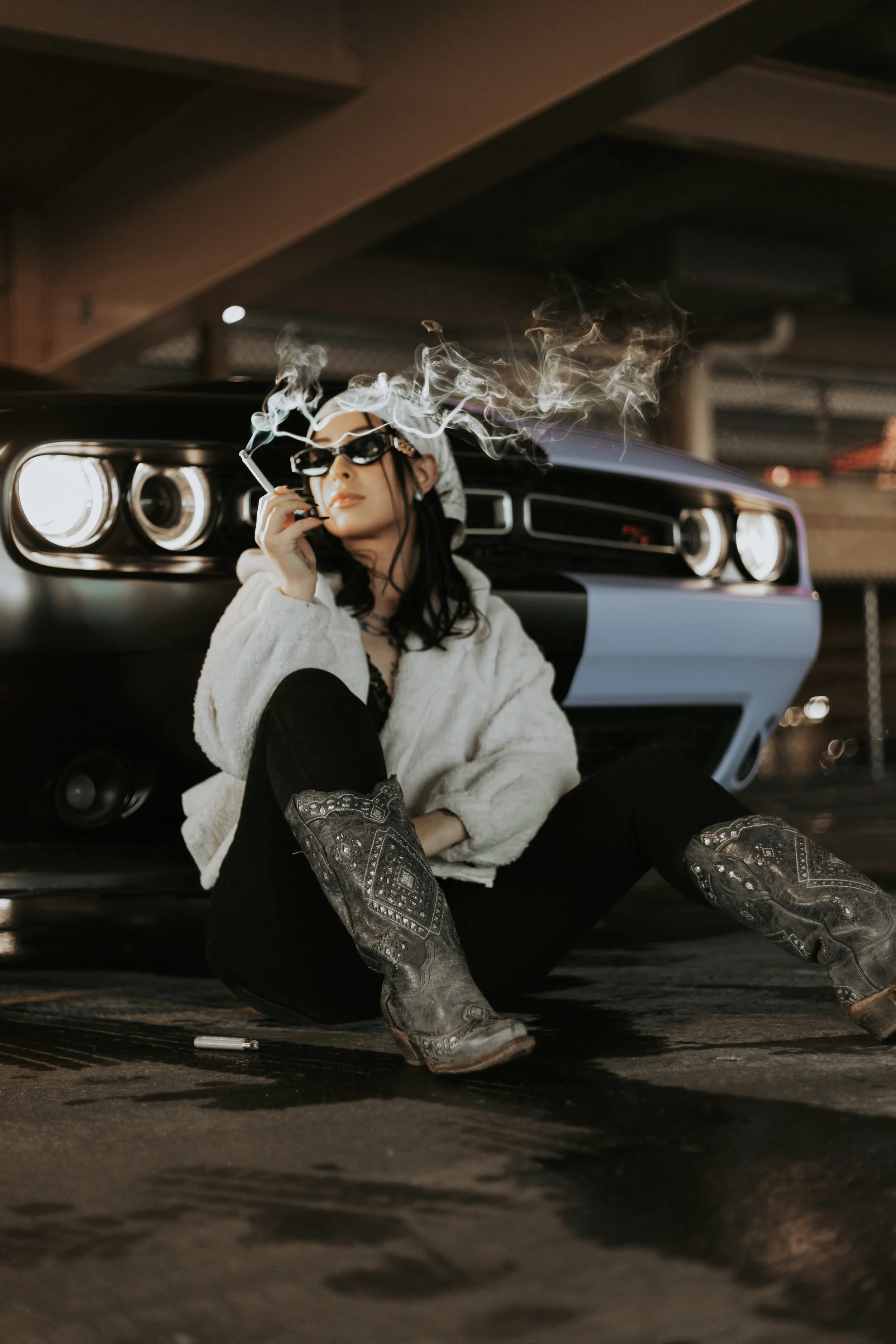 Woman smoking a cigarette in front of her Dodge Challenger in a moody editorial portrait