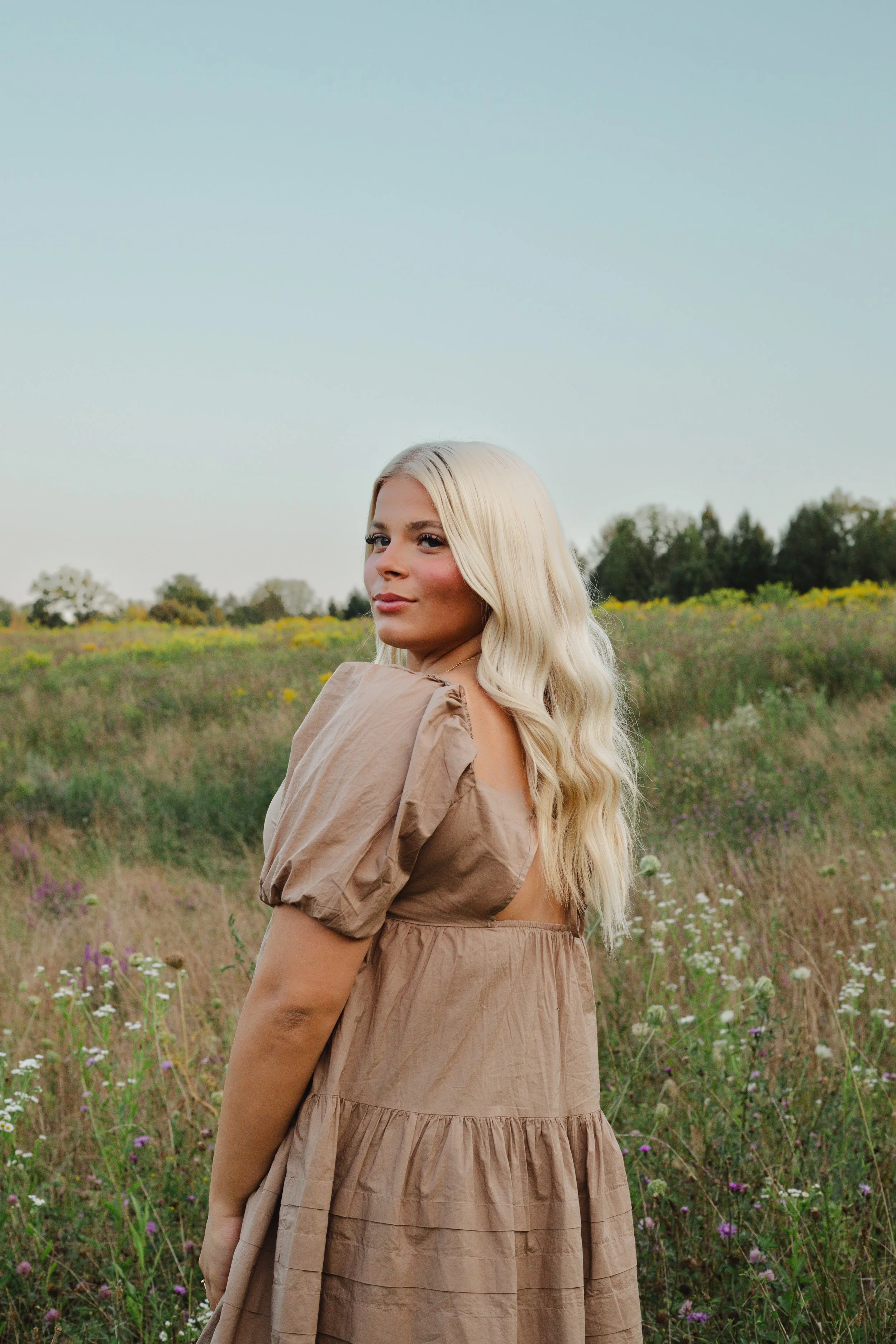 Woman in a flowy tan dress standing in a field of wildflowers, lifestyle photography in Central New York