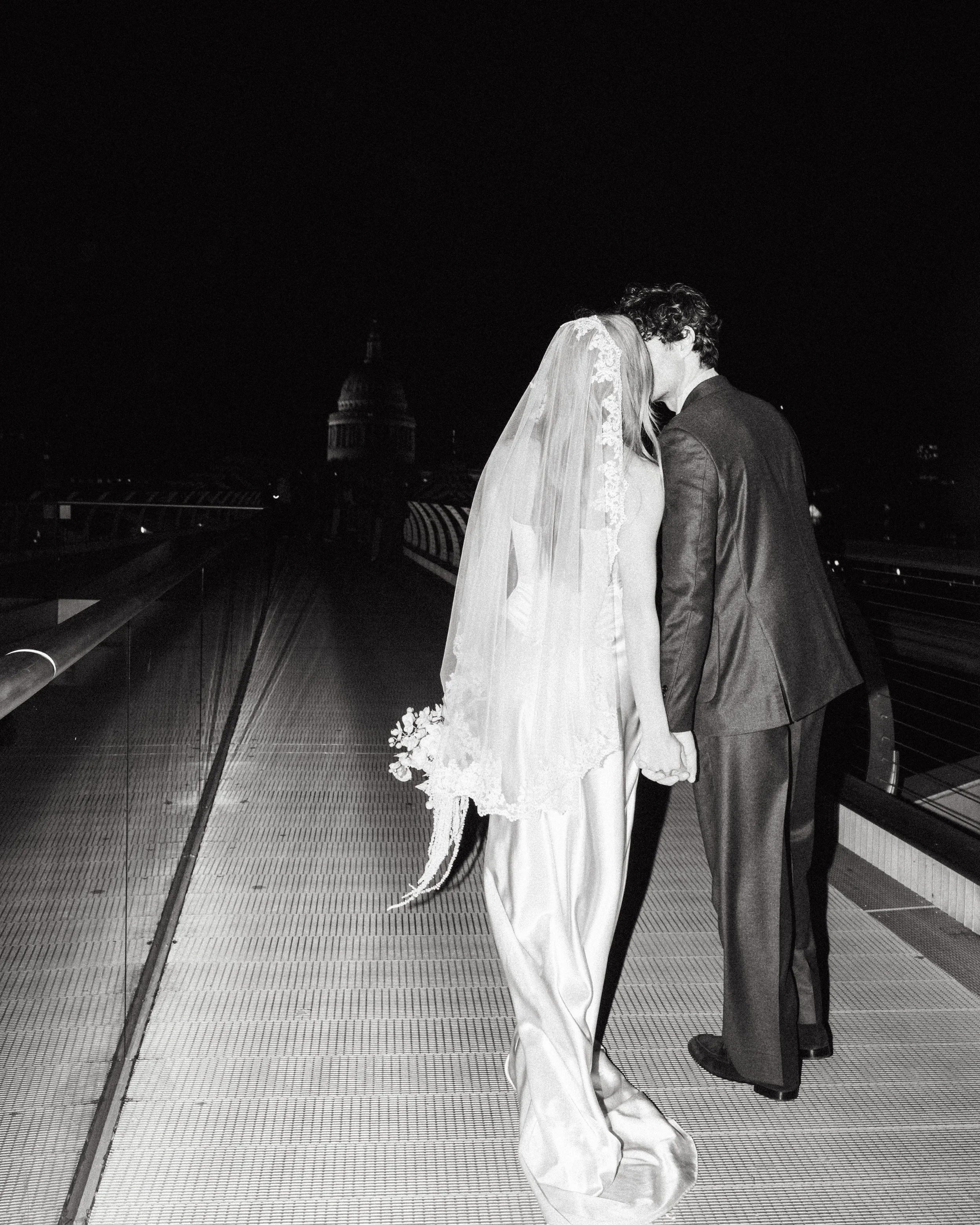 Earth Bridal bride in a long bias cut dress and handmade veil with her groom at night, London bridal atelier