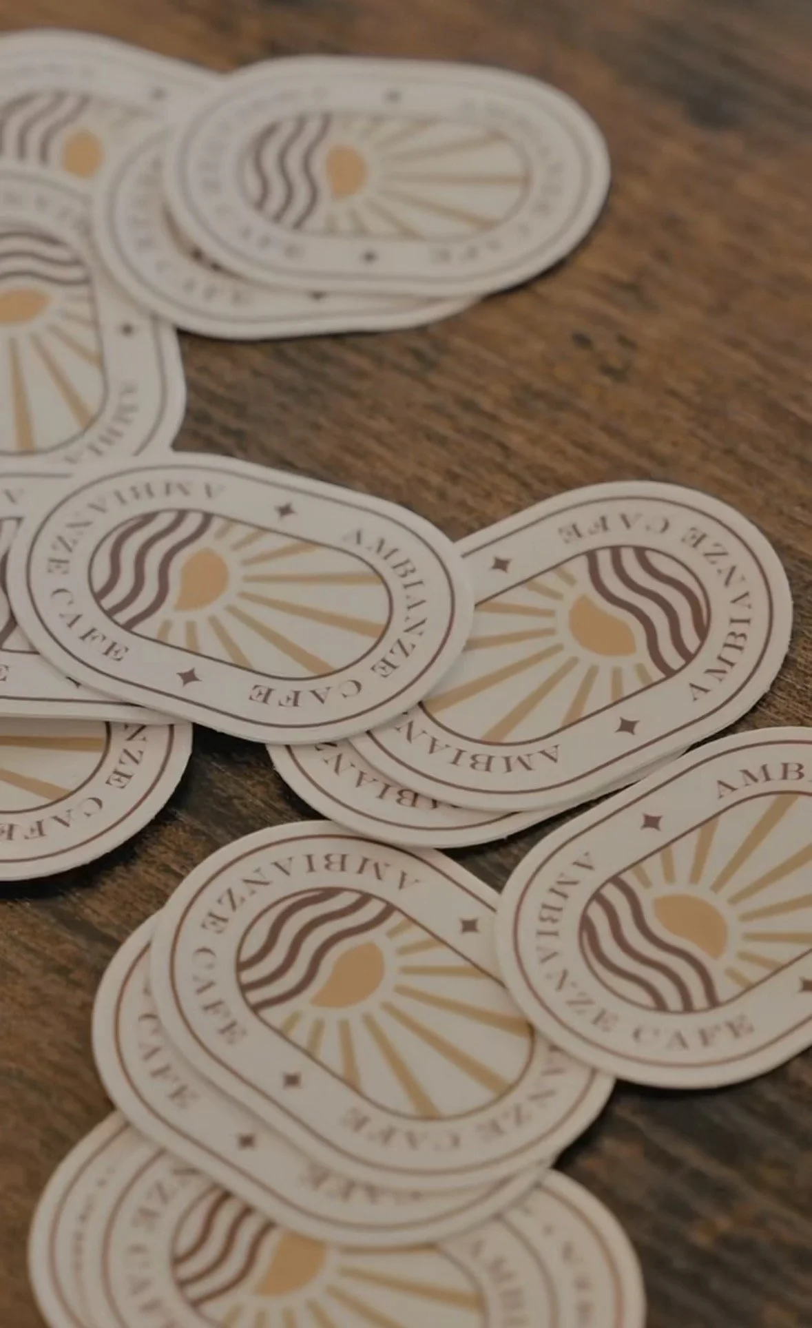 Several circular stickers with a sun and wave design and the text "Amberian Cave" scattered on a wooden surface.