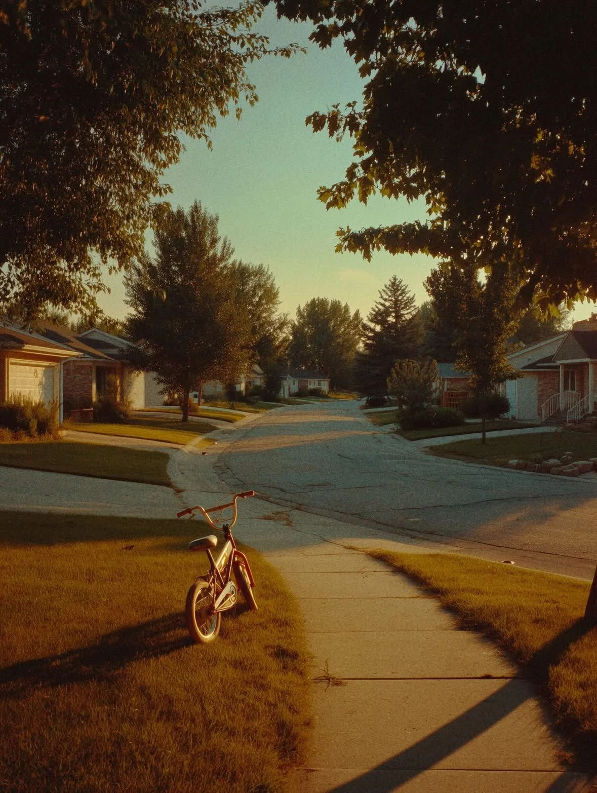 A peaceful suburban neighborhood street during sunset with a pink bicycle on the sidewalk in the foreground and houses surrounded by green trees. A neighborhood street in Eastern North Carolina