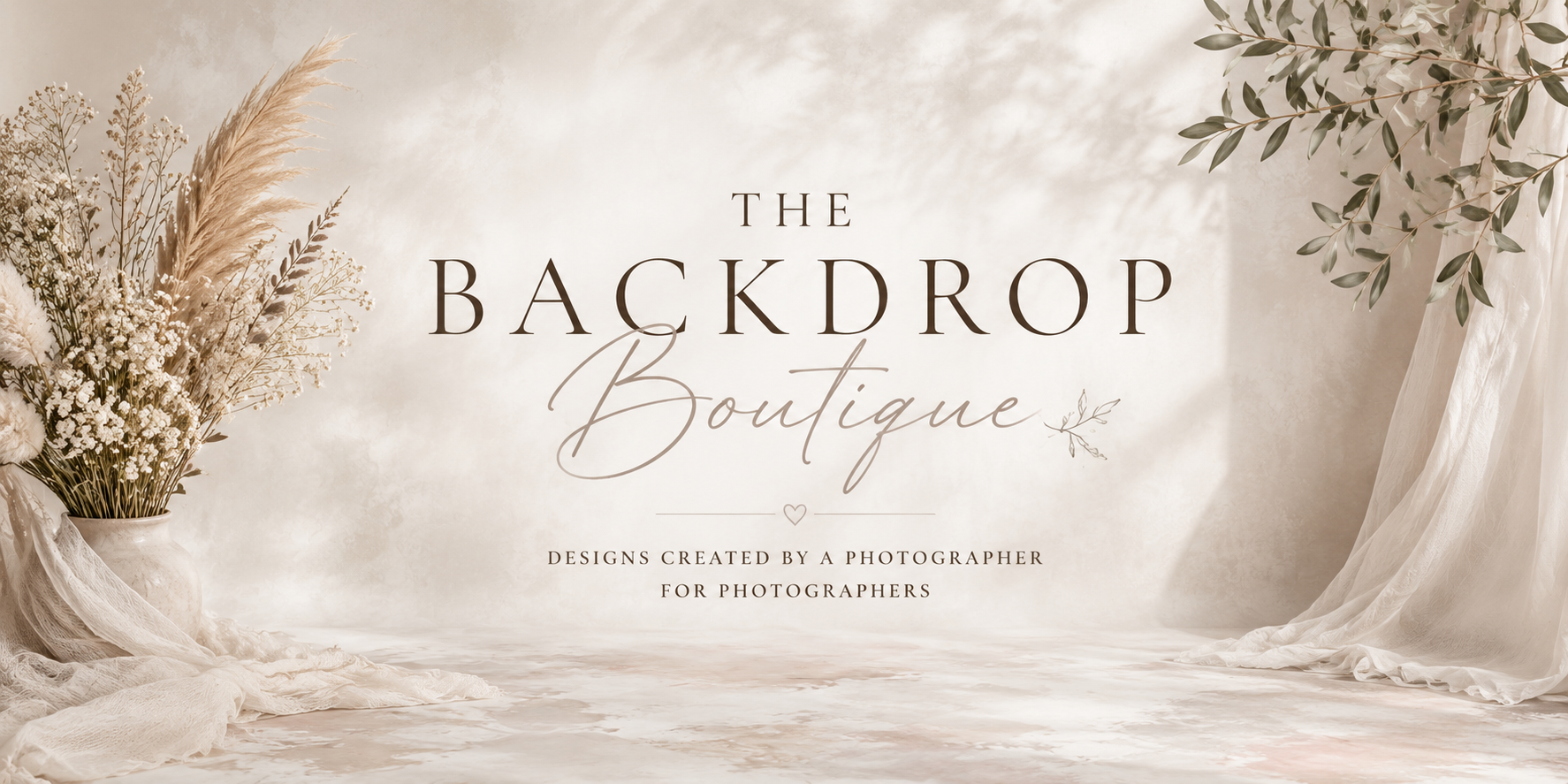 Elegant backdrop with neutral tones, floral arrangement on the left, draped fabric on the right, and text reading "The Backdrop Boutique" and "Designs created by a photographer for photographers."