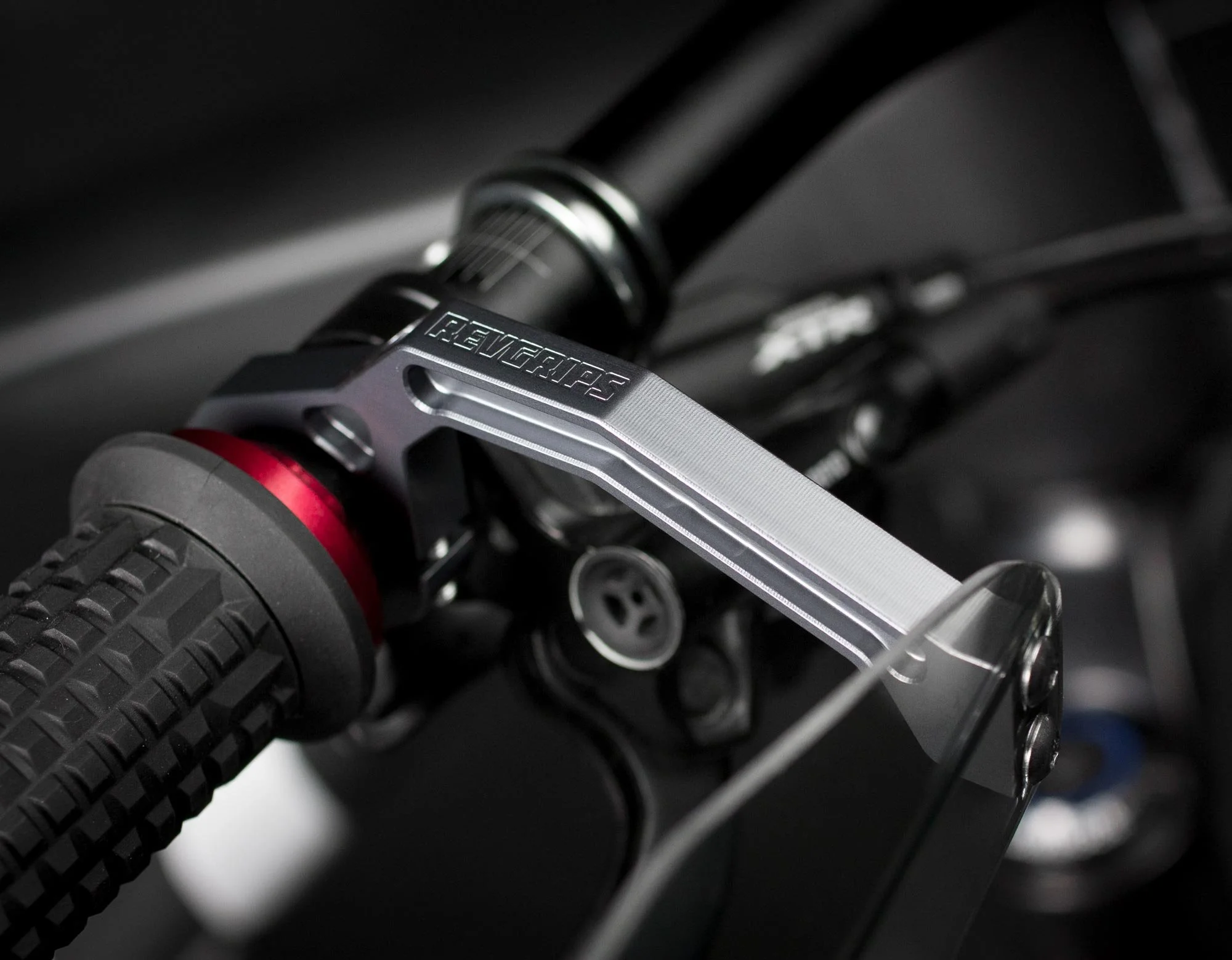 Close-up of a motorcycle handlebar with a textured grip, brake lever, and suspension component.