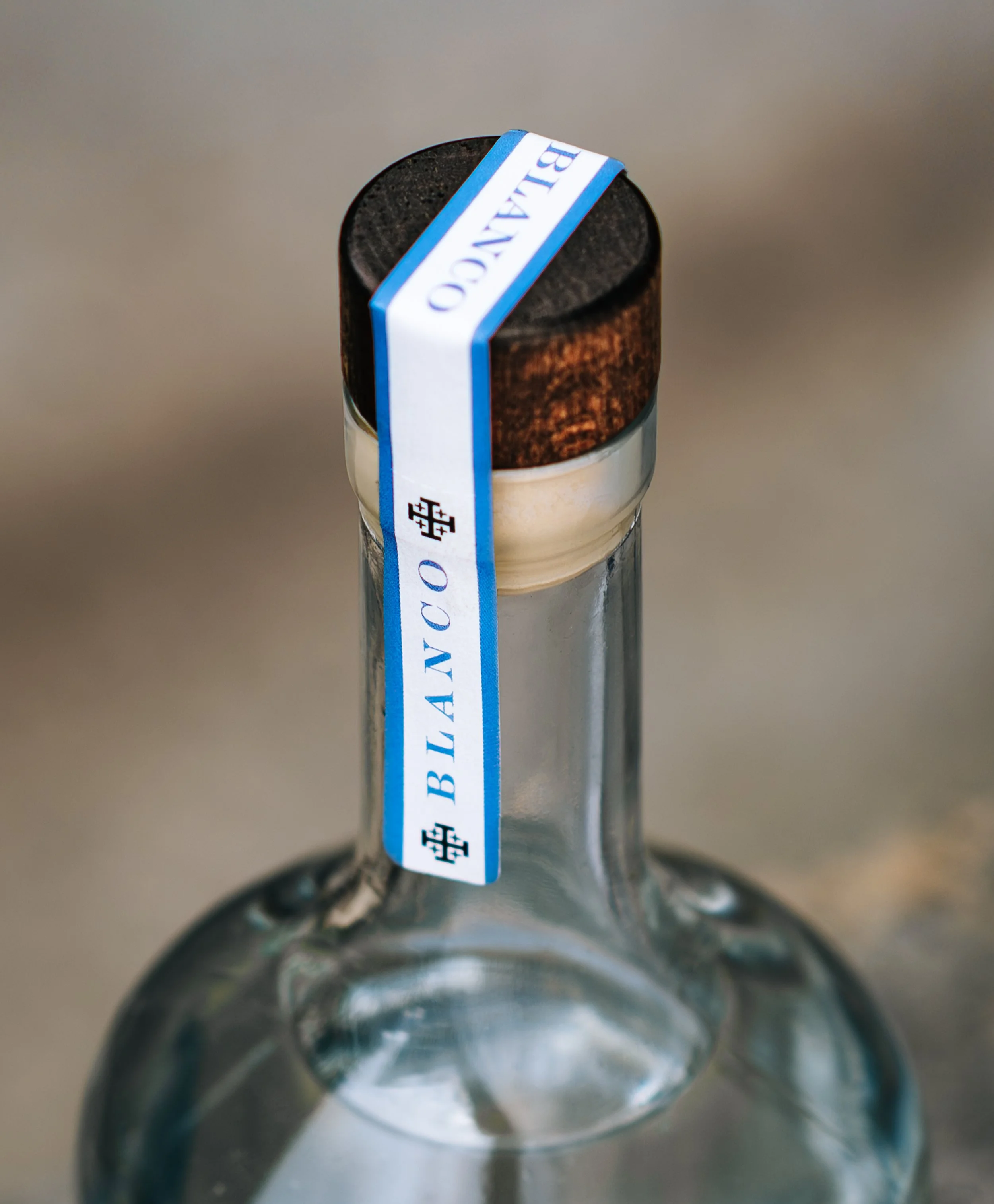 Close-up of a glass bottle with a metal cap and a blue and white label with small black text.