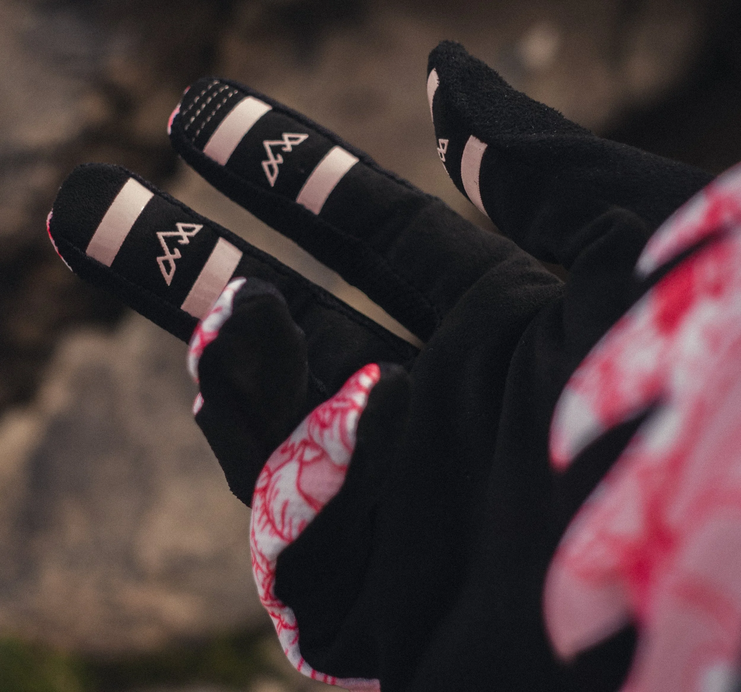 Close-up of a person's foot wearing a black sock and a black shoe with pink and white details, on an outdoor surface.