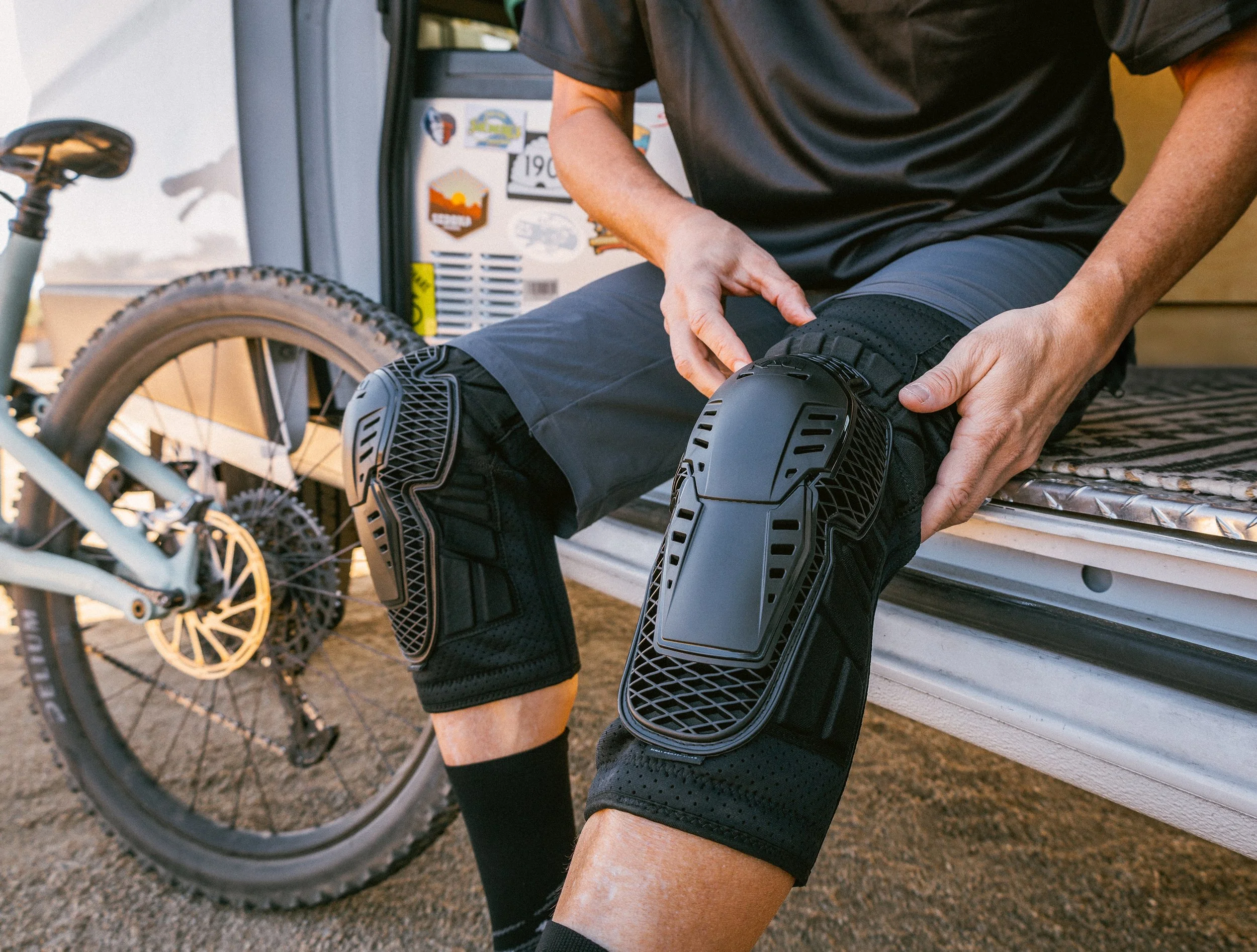 catalog photography of rider putting on protective gear with mountain bike