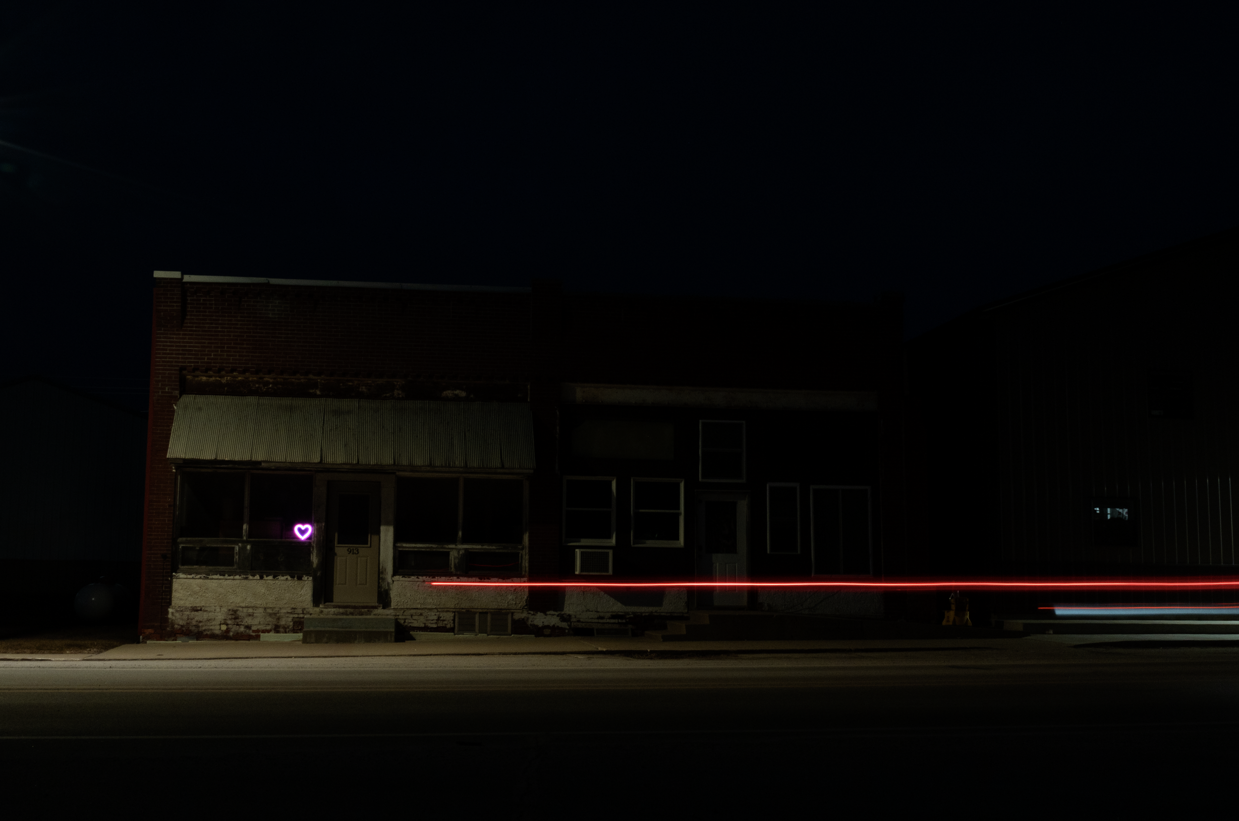 Empty brick buildings on a dark street with taillights flashing past