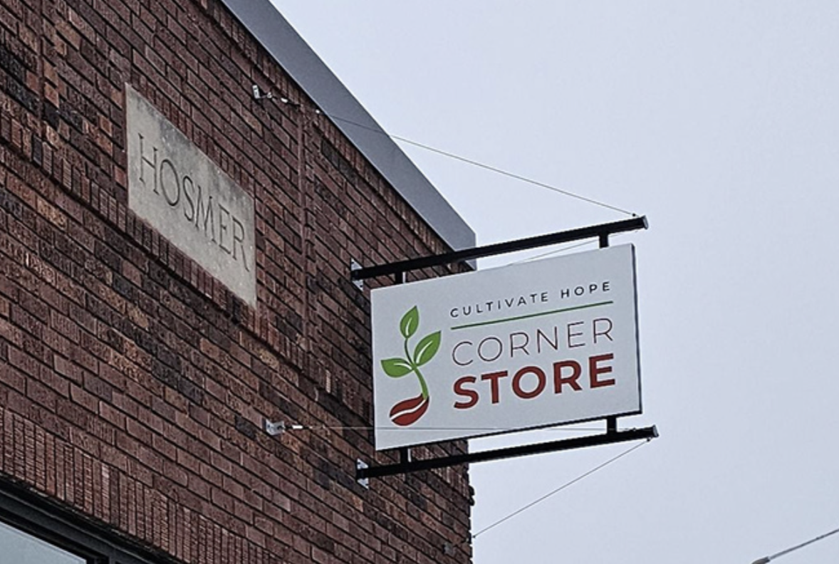 Sign on a brick building that says "Cultivate Hope Corner Store"