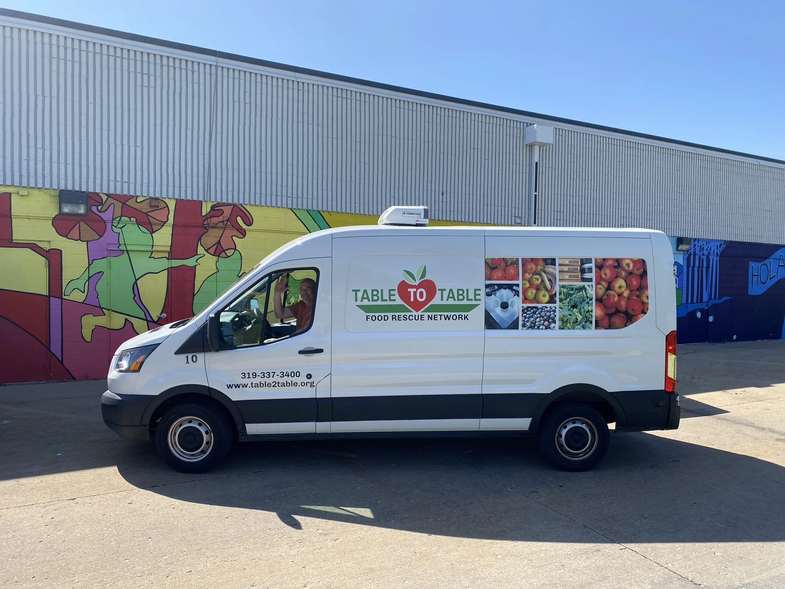 White Table to Table van in front of a building with a mural