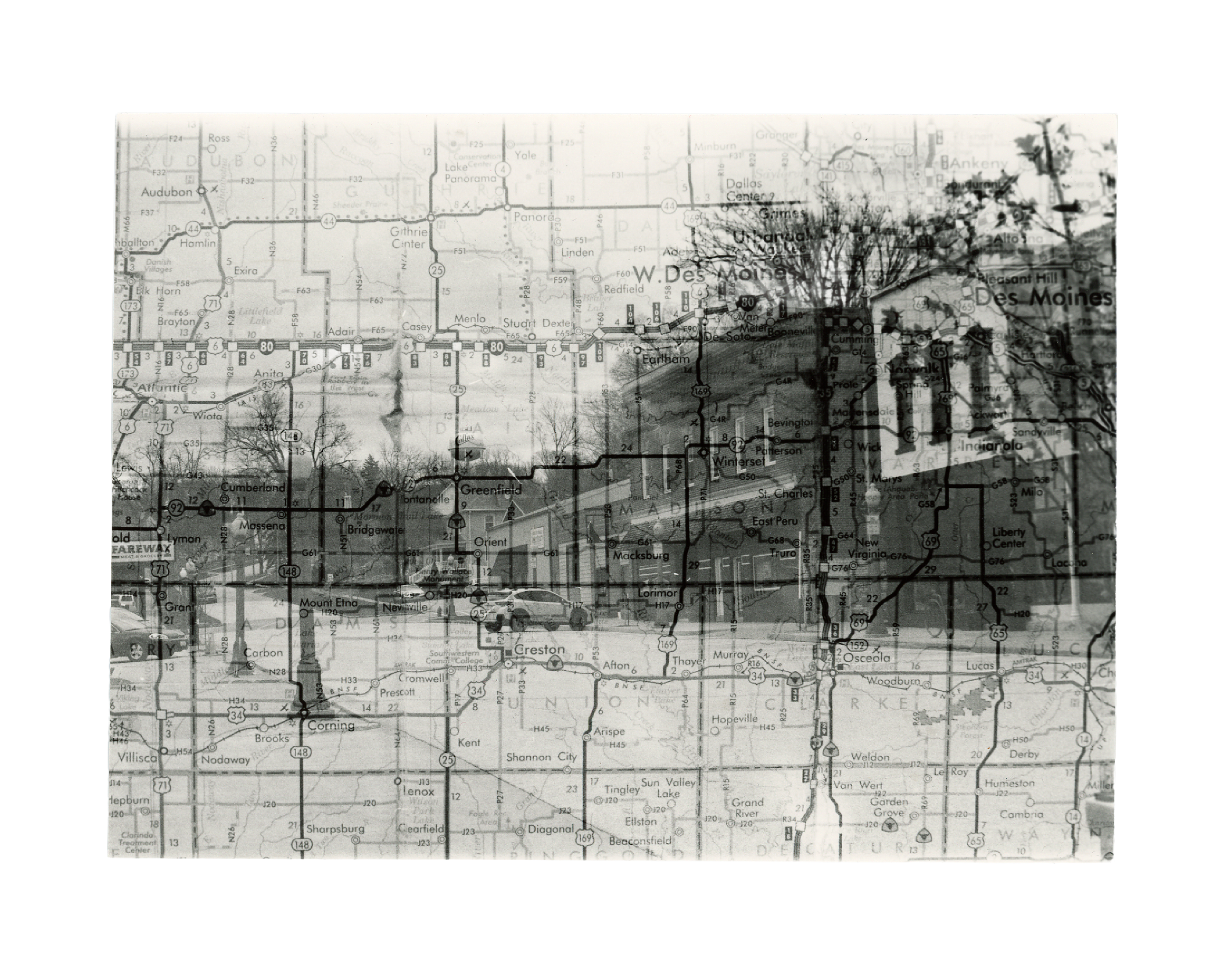 A black and white film double exposure image of a town scene with a map overlaid