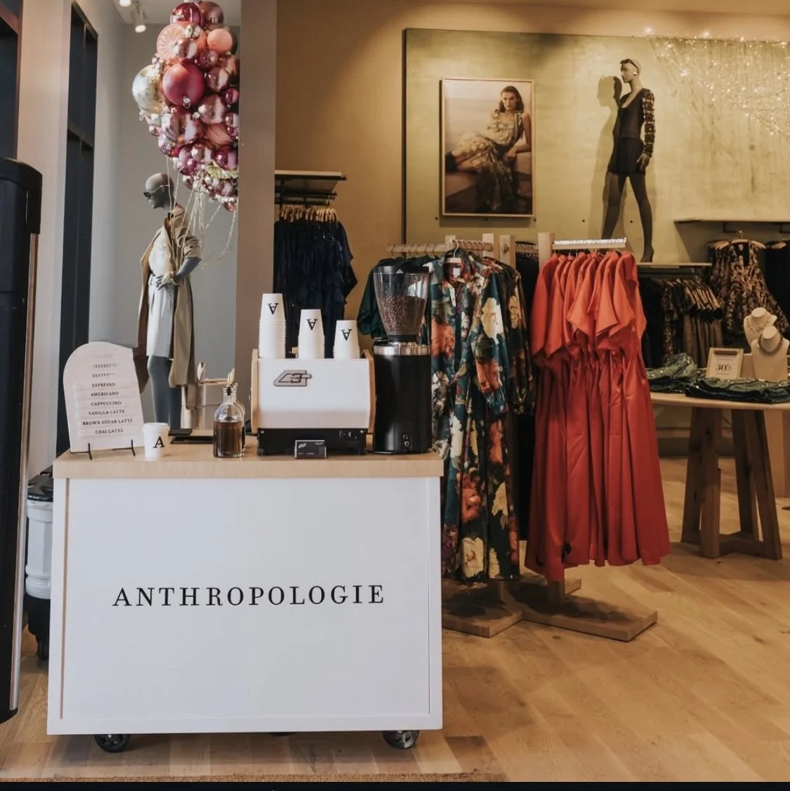 custom coffee cart Interior view of a clothing boutique with displays of dresses, mannequins, and accessories, including balloons and a coffee cart.