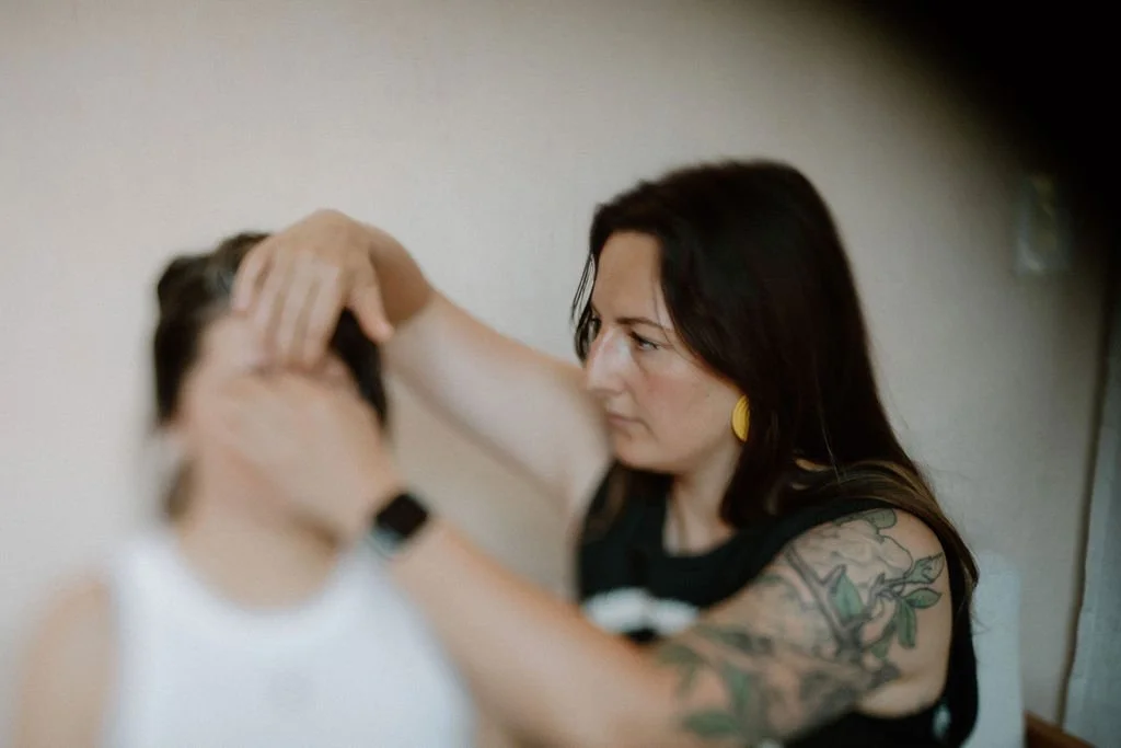 Ale concentrates as she performs Craniosacral Therapy (CST), a form of gentle body work and energy work. Her right had rests on her client's forehead, while the other hand gentle cups the bridge of their nose.