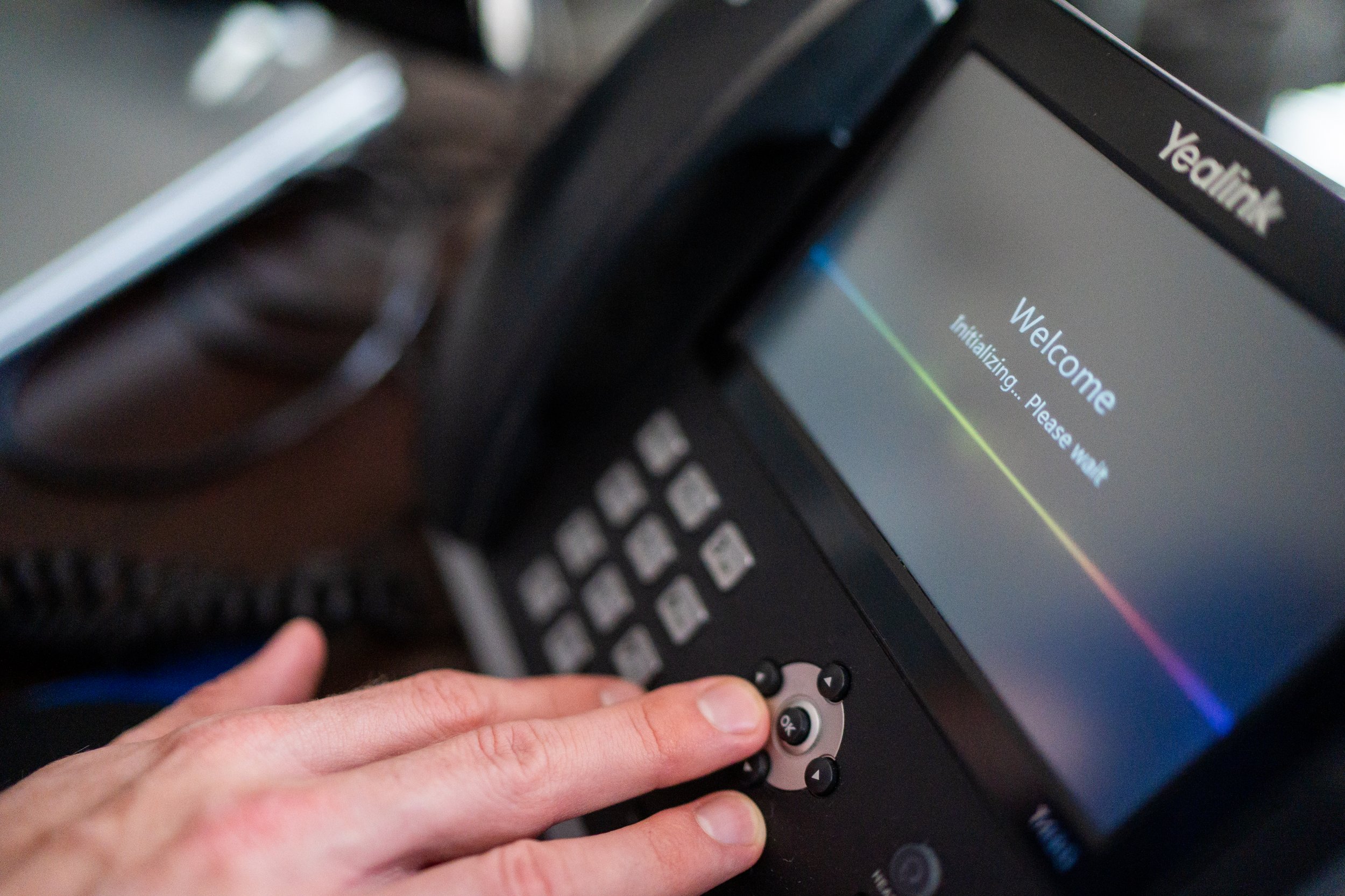 Close-up of a person's hand pressing a button on a contextual color touchscreen device displaying the word 'Welcome' and a message to initializing.