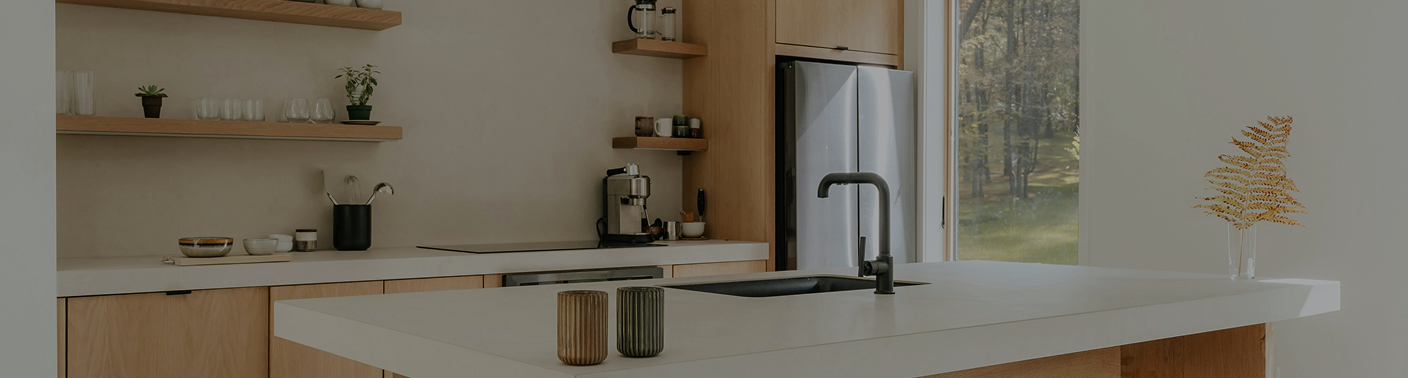 Modern kitchen with white countertops, wooden cabinets, open shelves with plants and dishes, a refrigerator, and a window overlooking a yard.