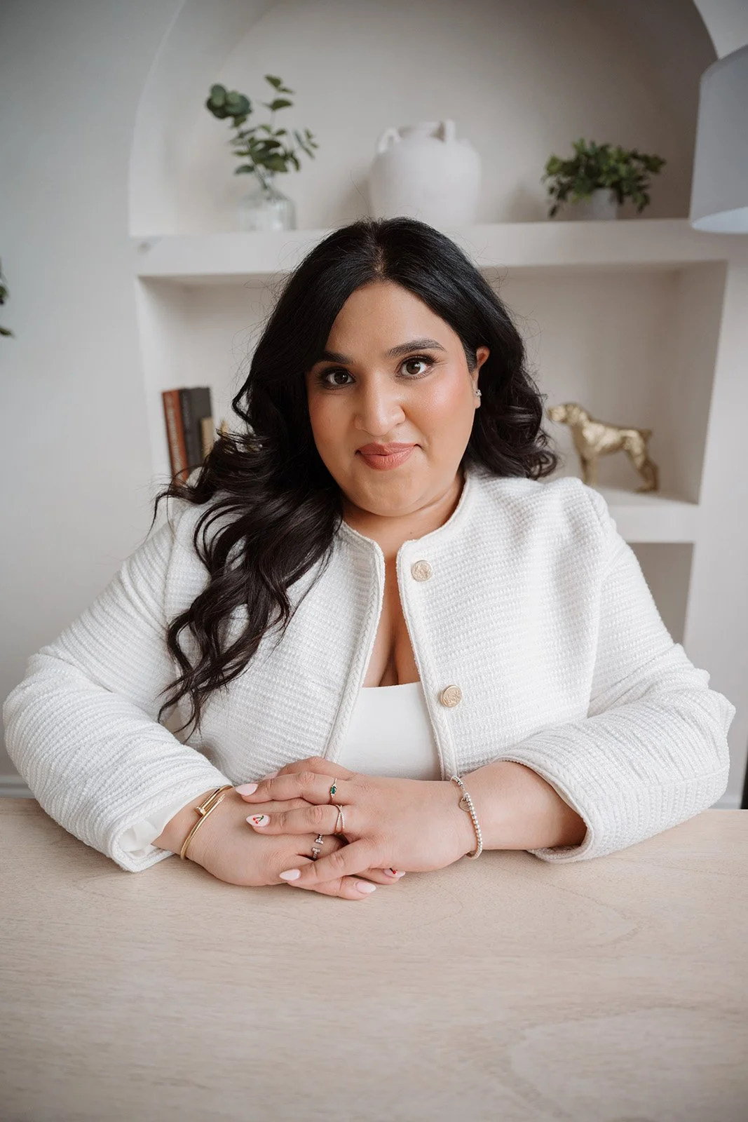 Lyndsi Seth photography- A professional headshot of a woman in a white textured blazer leaning forward on a light wooden table
