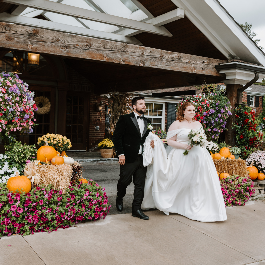 Lyndsi Seth photography- A newlywed couple holding hands and walking together outdoors, with the groom in a classic tuxedo and the bride in an off-the-shoulder gown