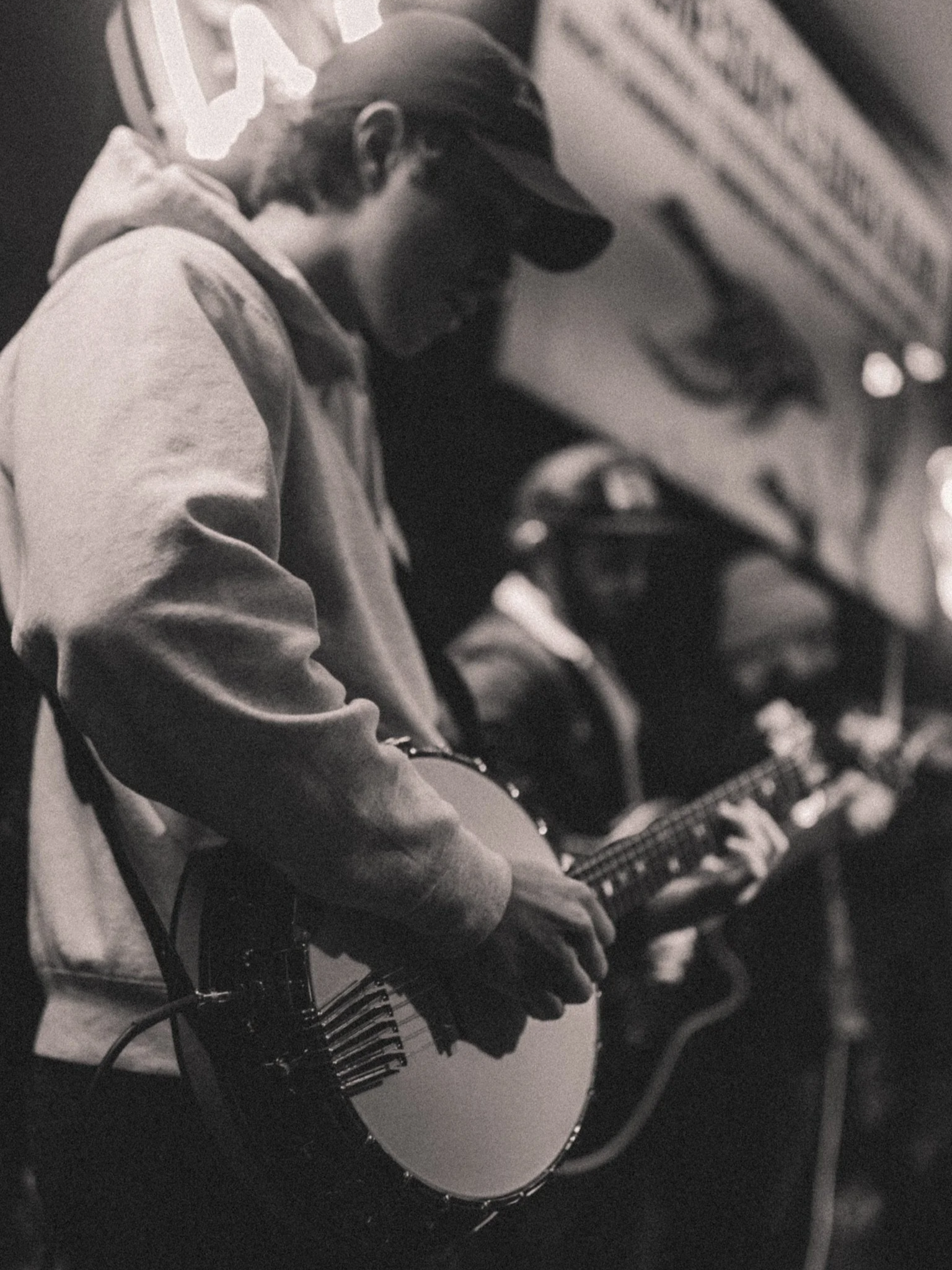 A person wearing a hoodie and a baseball cap is playing an acoustic guitar, with a focus on their hands and the guitar.  Nashville Guitar Lessons Zoom Guitar Lessons Virtual Lessons In Person Guitar Lessons Session Work Audition Prep