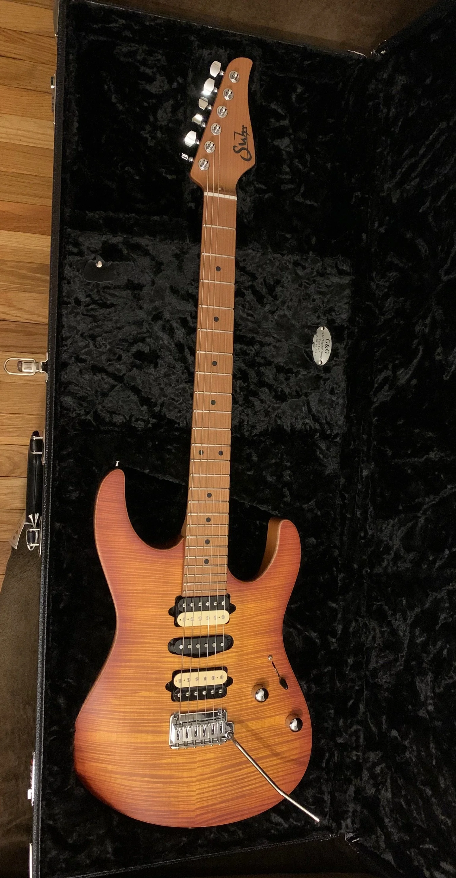 Electric guitar with a sunburst finish inside a black hard case with a plush interior.