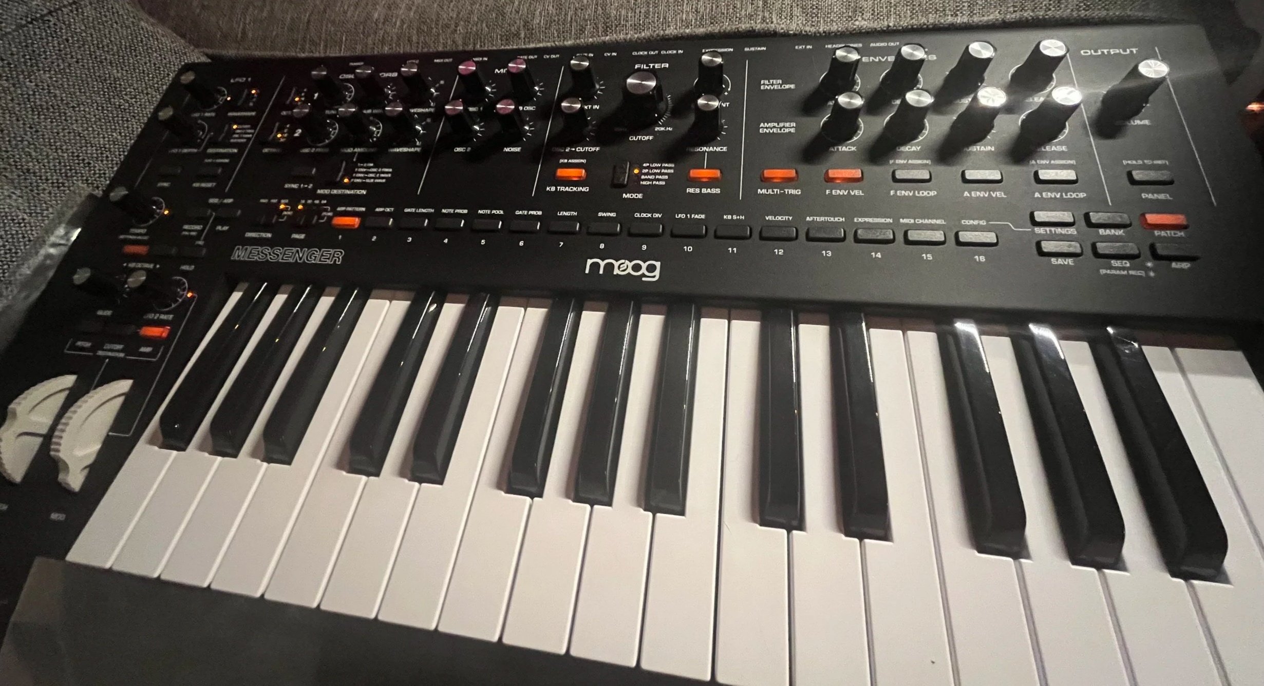 A Moog Messenger synthesizer with black knobs and white keys, set on a gray surface.