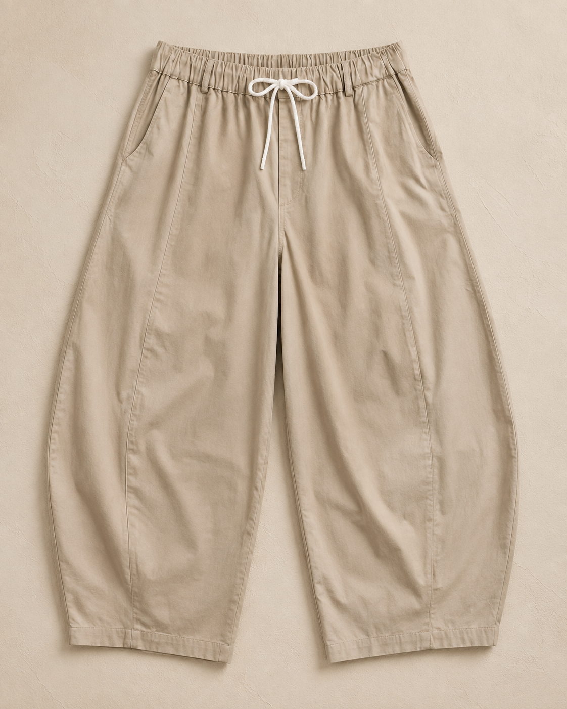Flat lay of The Flax Studio tan Esme Pant, showing the elasticated drawcord waist and curved-leg shape.