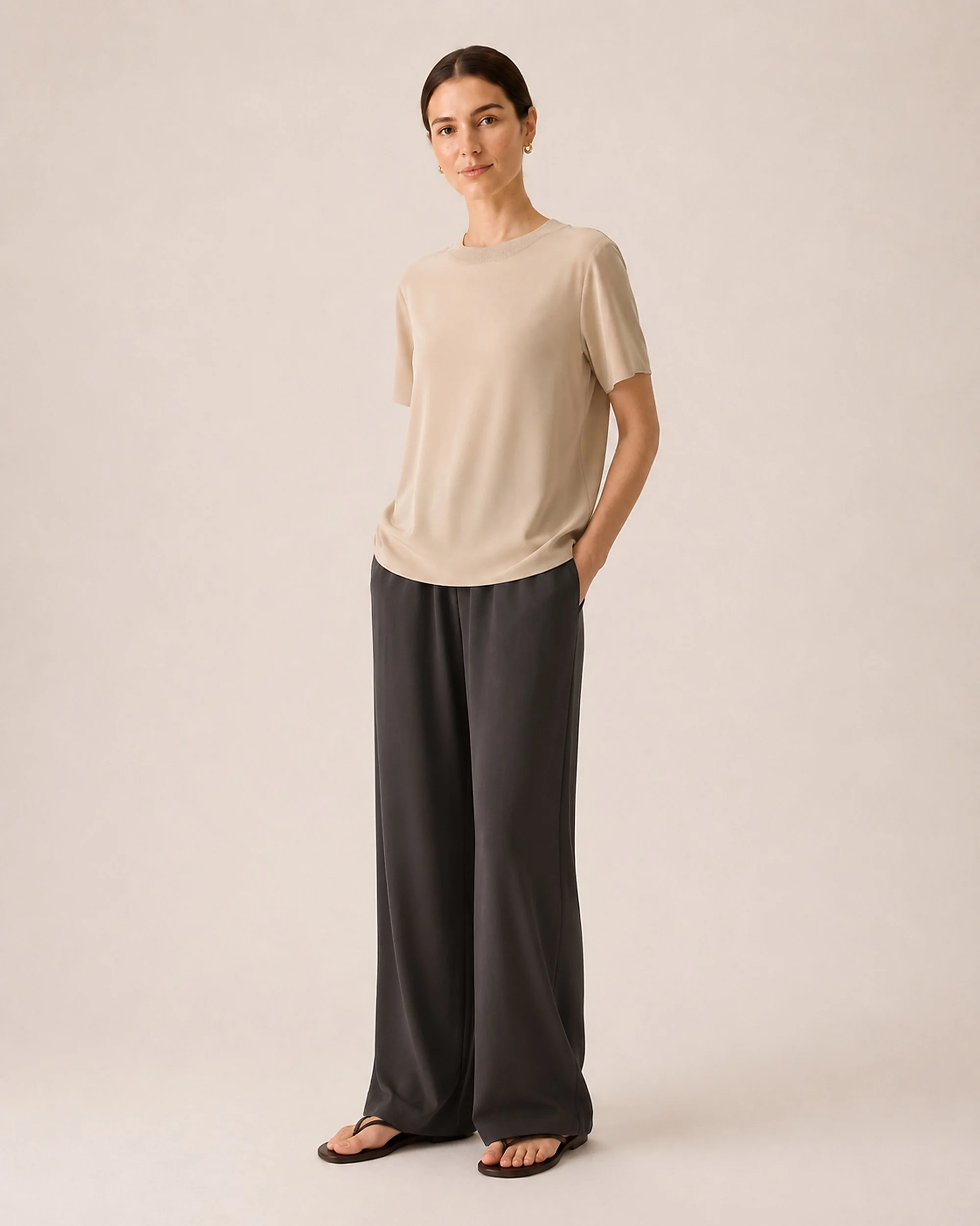 Full-length view of The Flax Studio beige Silk Crew Neck Top worn with dark wide-leg trousers.