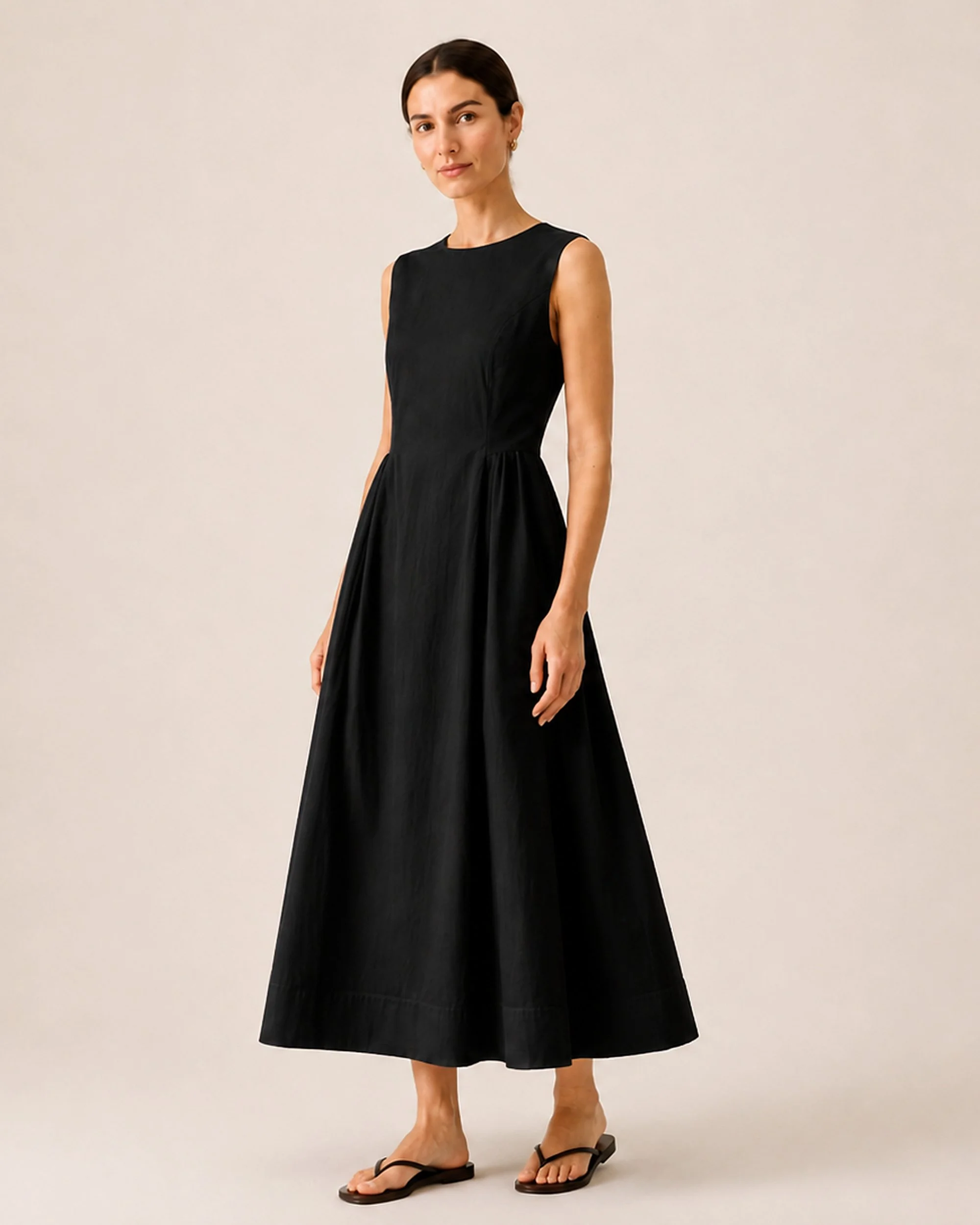 Angled front view of The Flax Studio black Tailored Dress, showing the skirt drape.