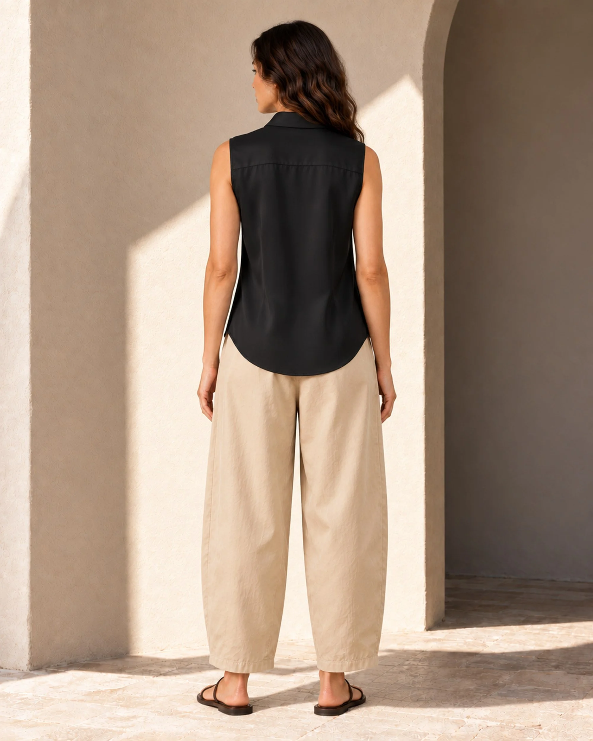 Back view of the black mulberry silk sleeveless blouse, showing the back yoke, shaping seams and curved shirttail hem.