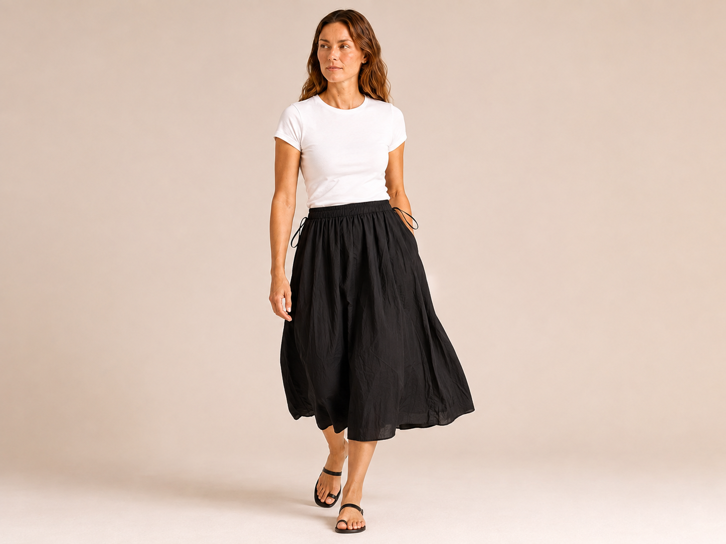 The Flax Studio black Cotton Tie Skirt in motion, showing the softly gathered cotton and midi length.