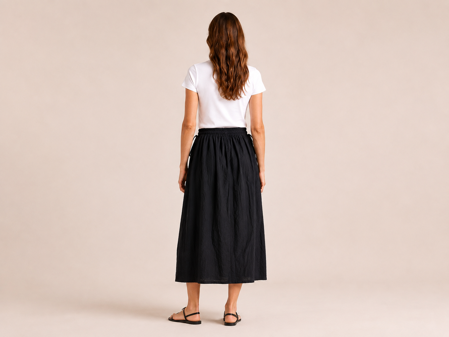 Back view of The Flax Studio black Cotton Tie Skirt worn with a white T-shirt.