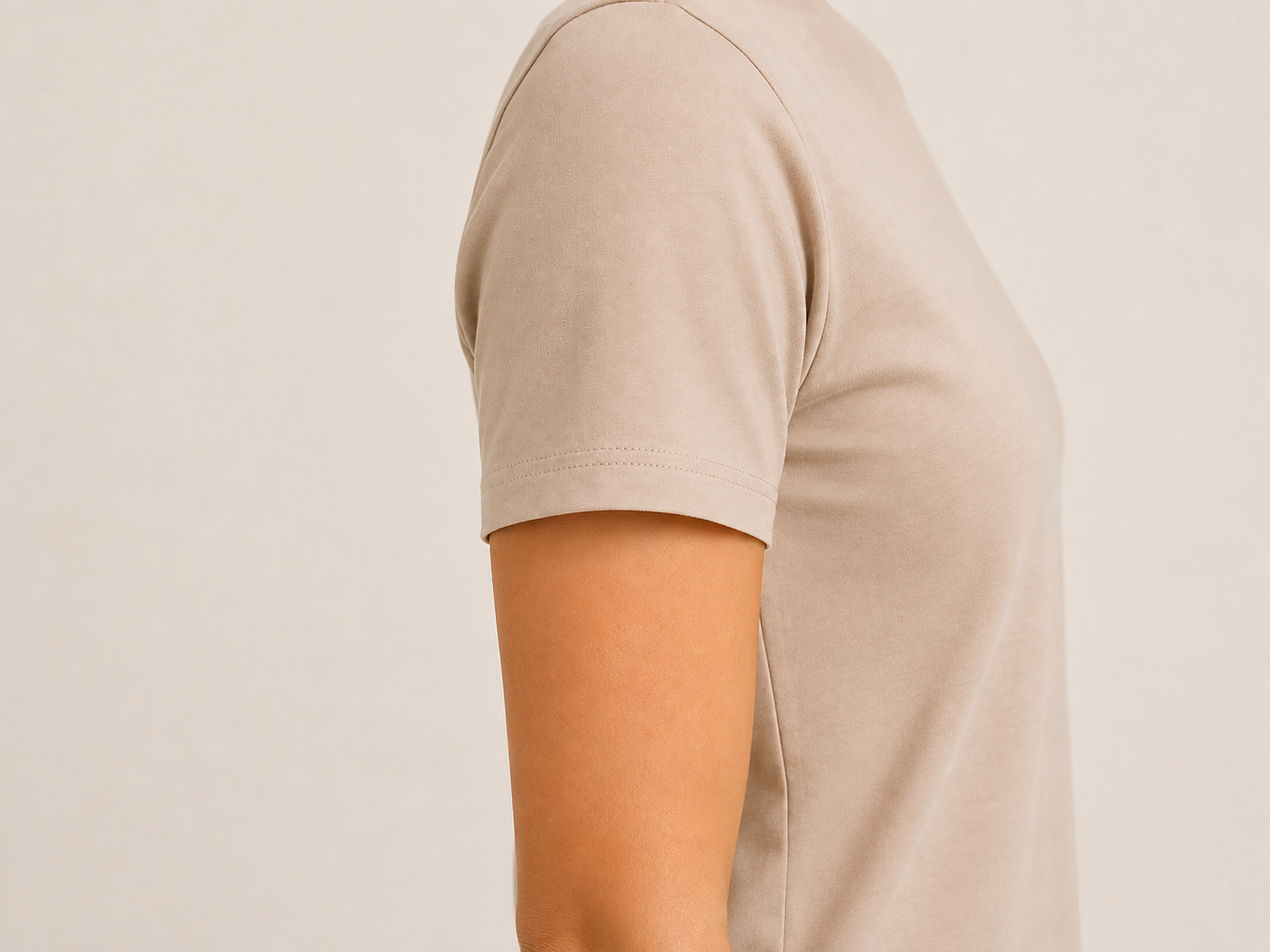 Close-up of The Flax Studio sand mercerised cotton T-shirt sleeve, showing the shoulder seam and stitched sleeve hem.