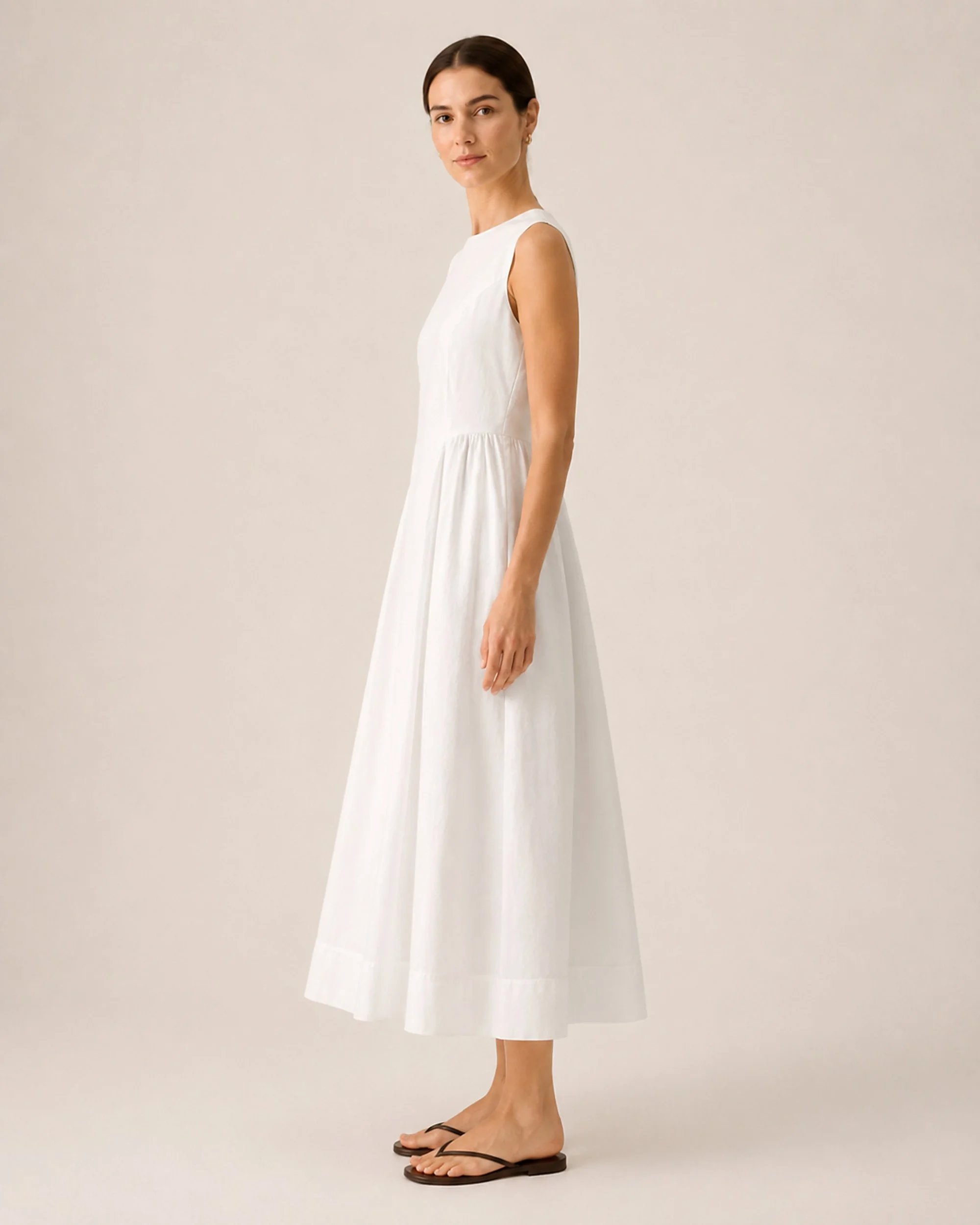 Side view of The Flax Studio white Tailored Dress, showing its fitted bodice and A-line silhouette.