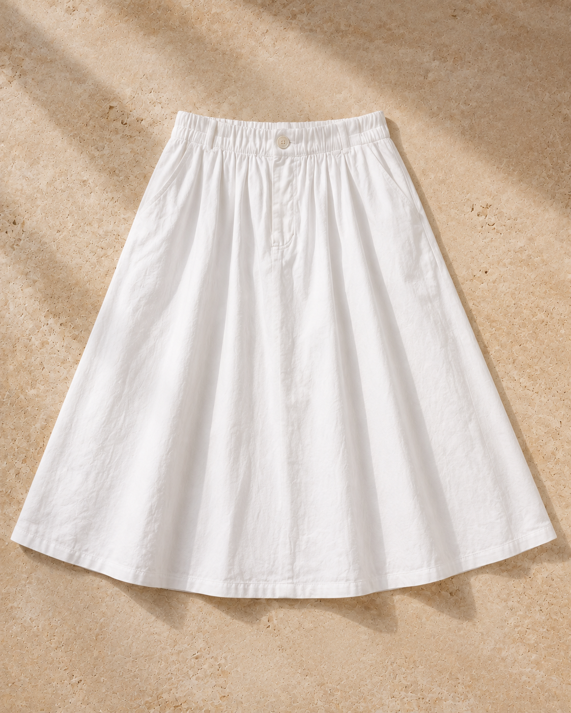 The Flax Studio white Button Front Skirt laid flat, showing its gathered elasticated waist and A-line midi shape.