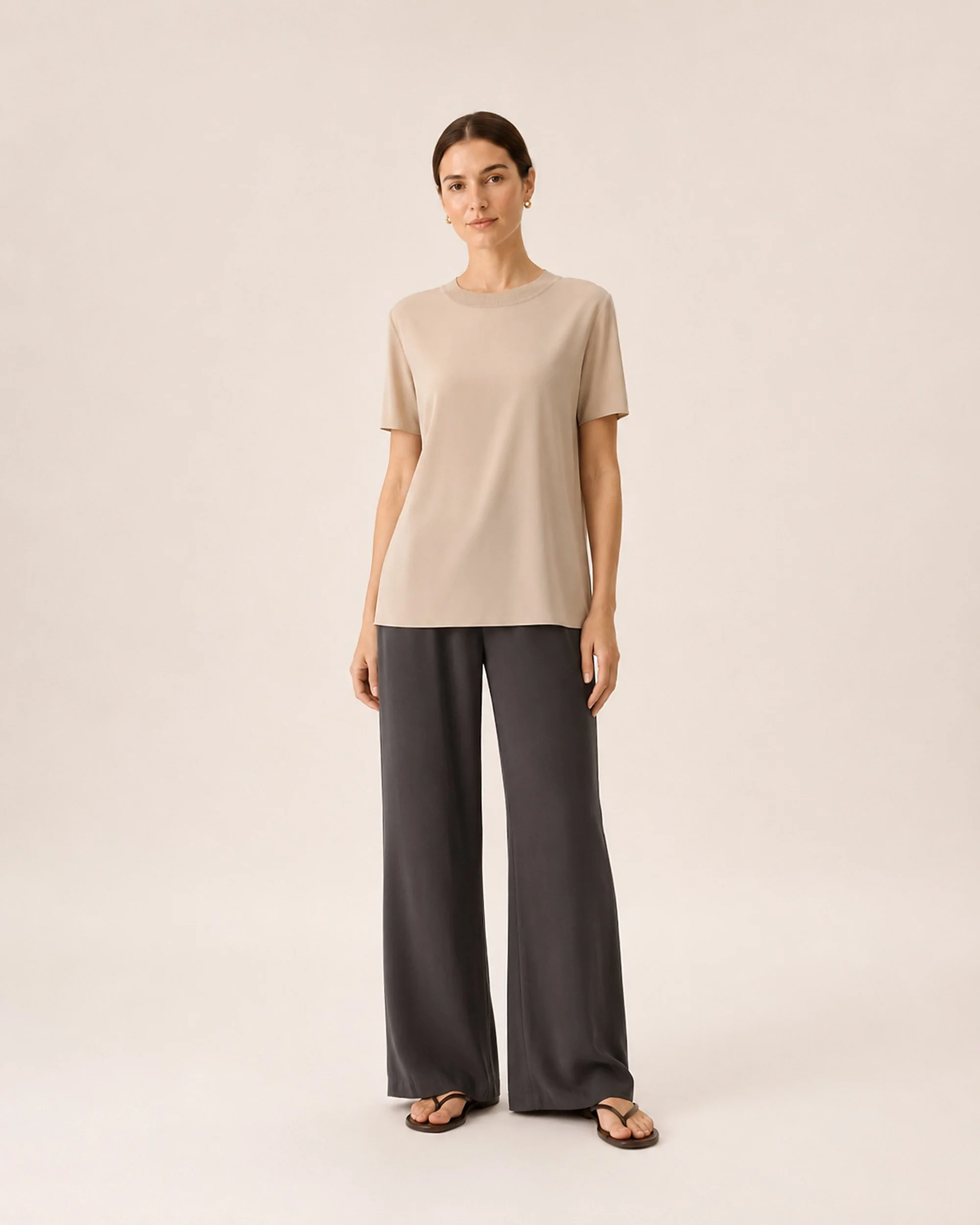 The Flax Studio Silk Crew Neck Top in beige, showing the alternative colour worn with dark trousers.
