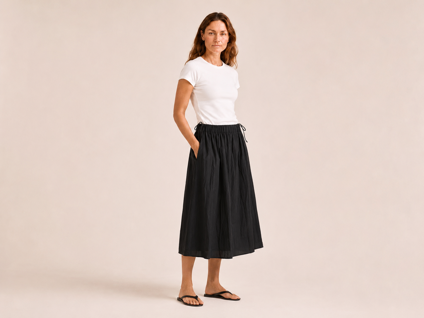 The Flax Studio black Cotton Tie Skirt worn with a white T-shirt, angled front view.